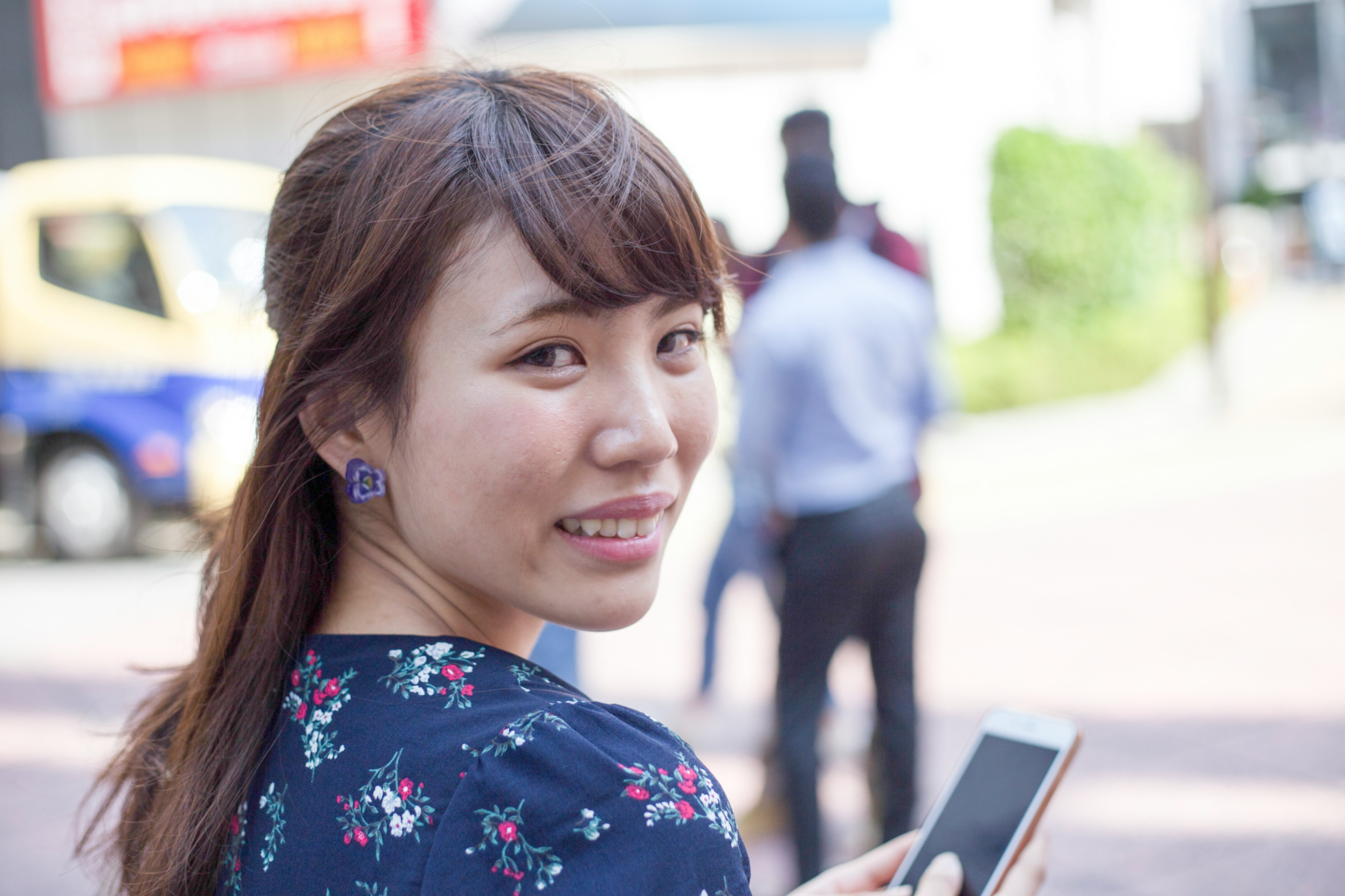 Donna sorridente con uno smartphone in una città