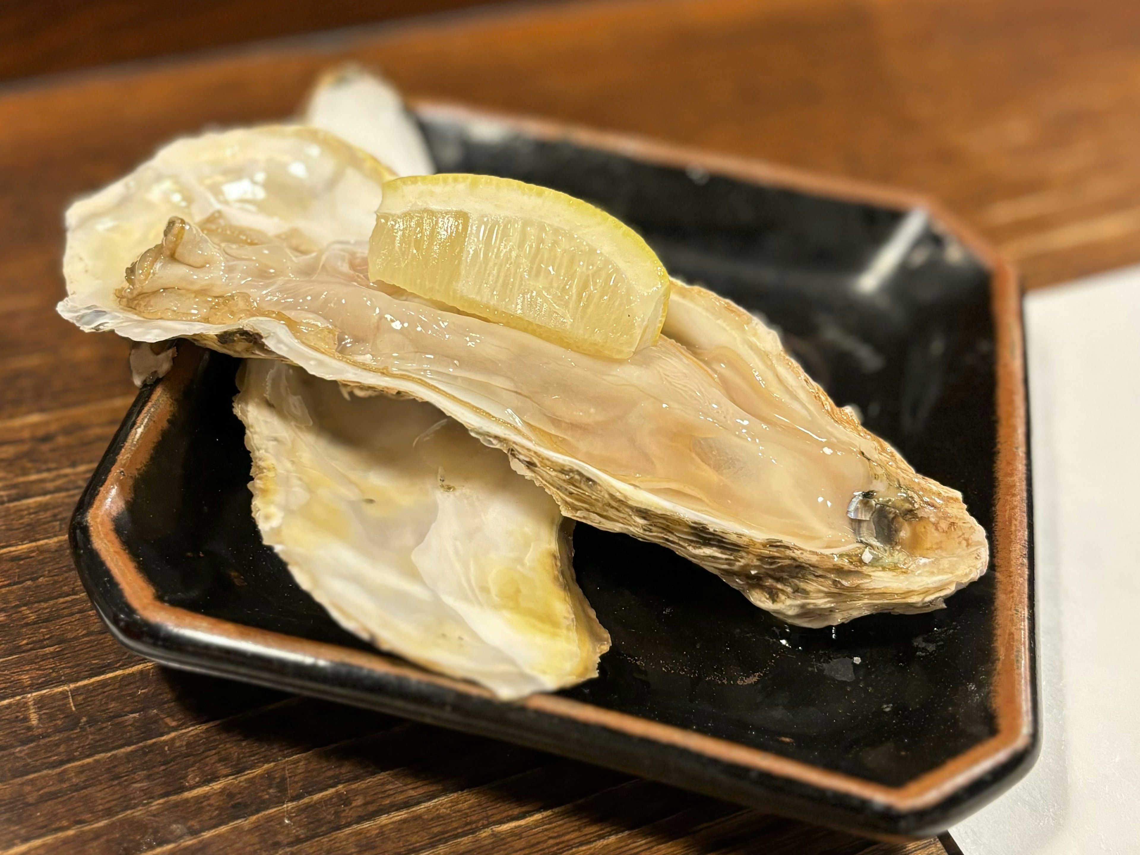 Huîtres fraîches servies sur une assiette noire avec une tranche de citron