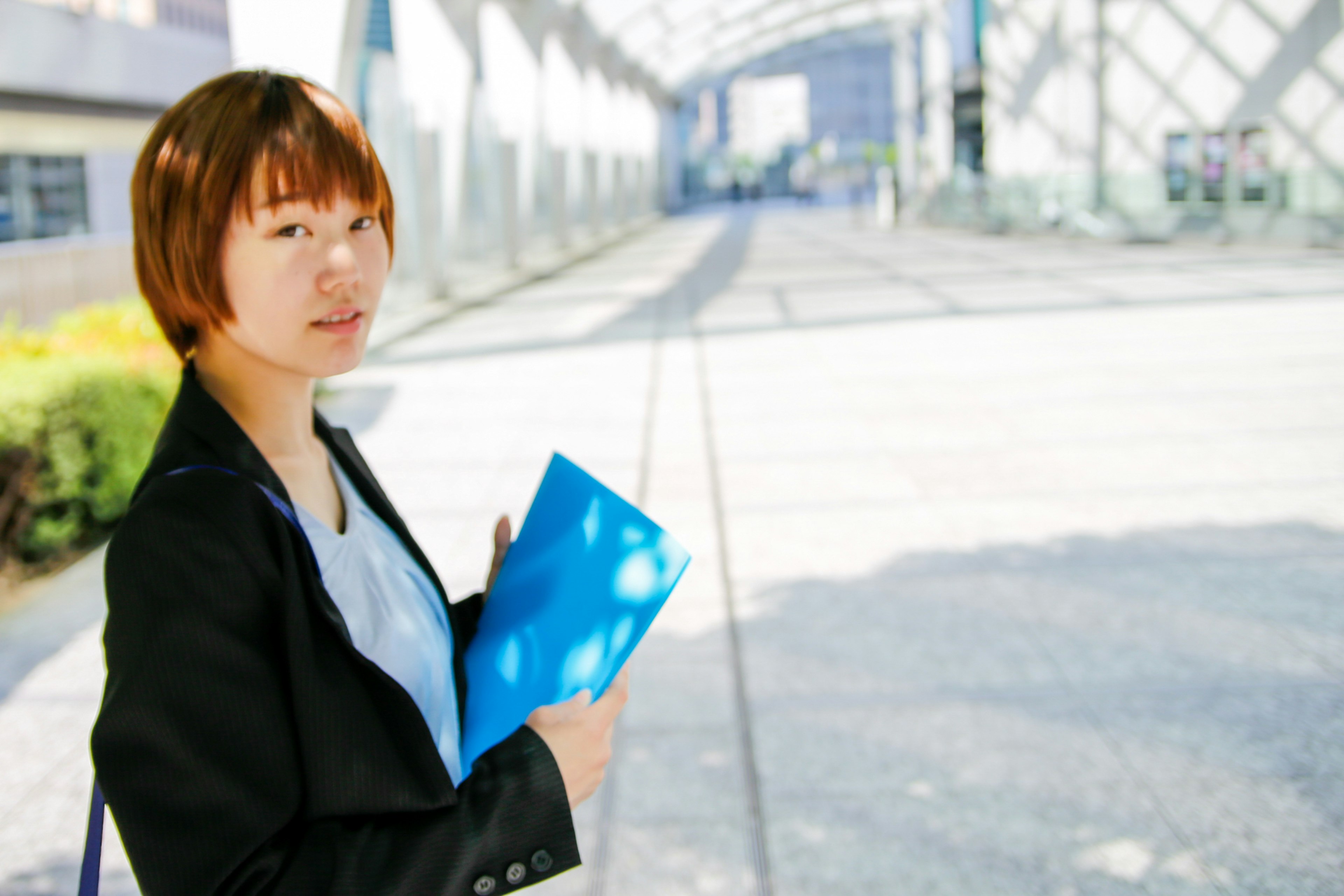 Seorang wanita berpakaian bisnis memegang folder biru