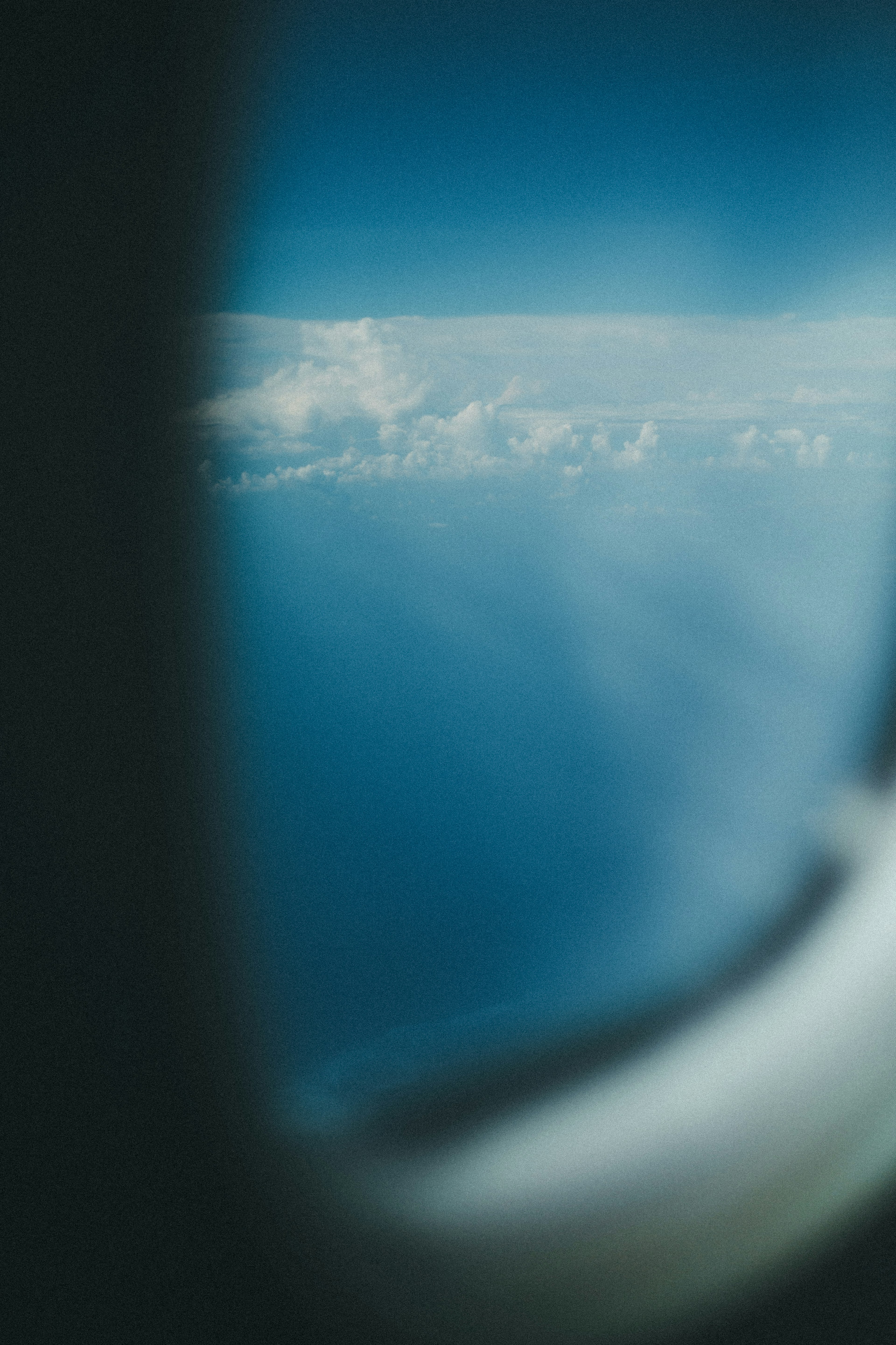 Blick auf den blauen Ozean und weiße Wolken von einem Flugzeugfenster