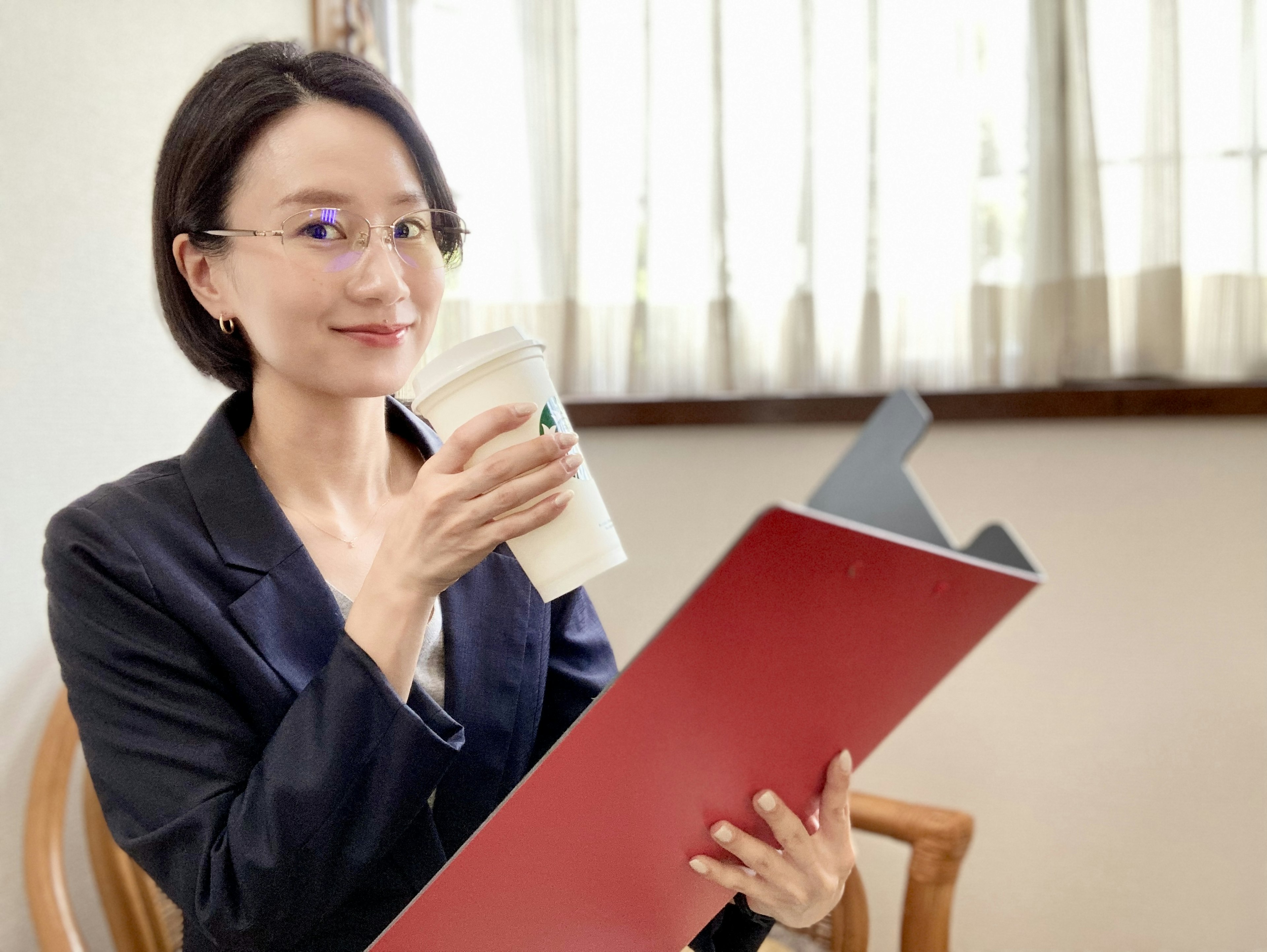 Femme tenant un dossier rouge et une tasse de café dans un bureau