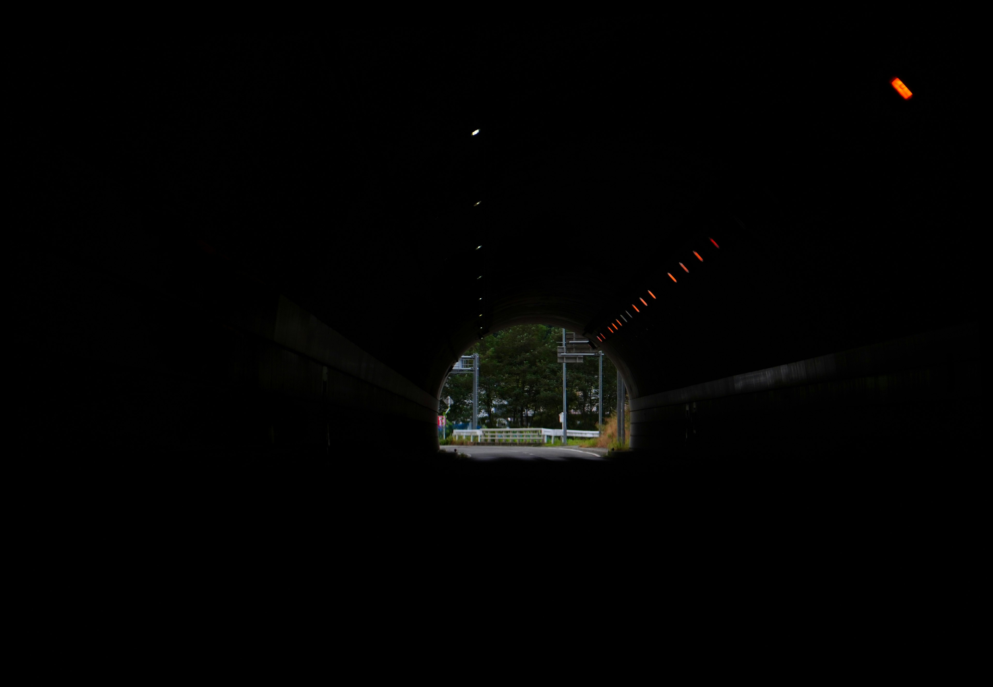 Bright exit visible from the dark tunnel with surrounding scenery