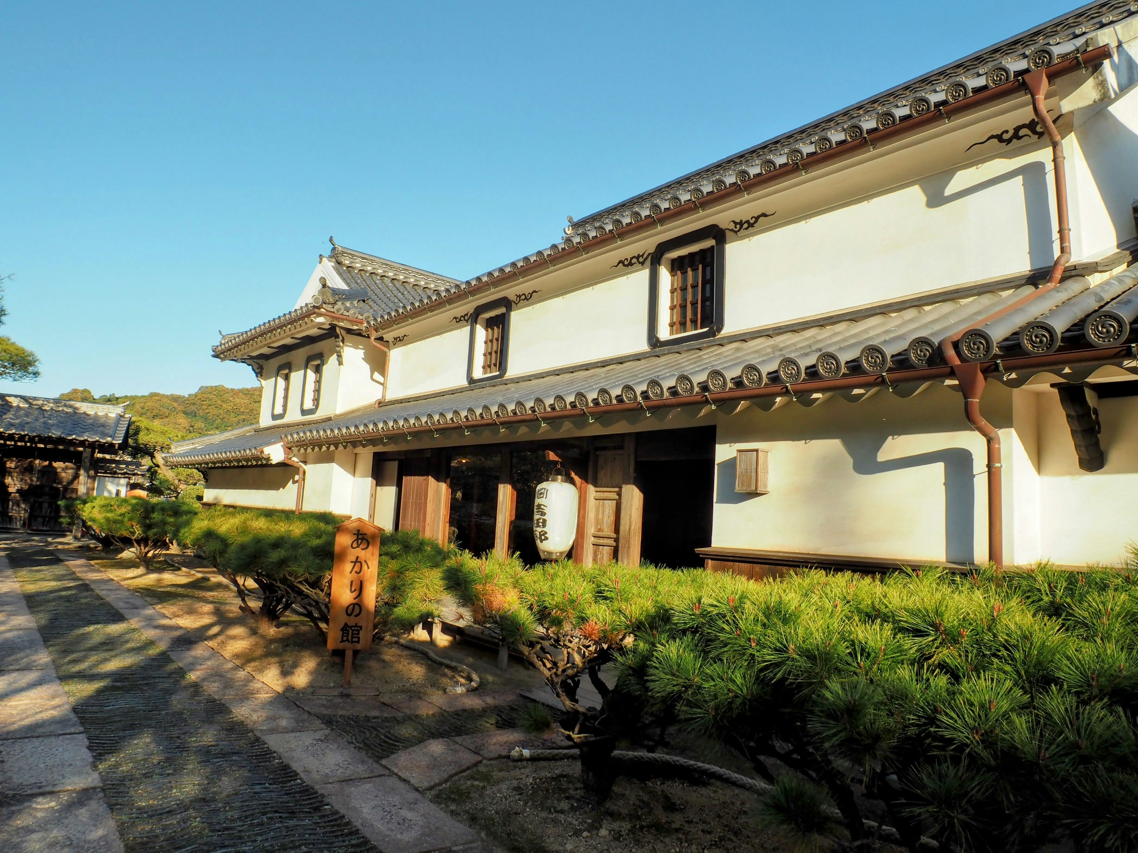 Äußeres eines traditionellen japanischen Gebäudes mit grünem Landschaftsbau unter blauem Himmel