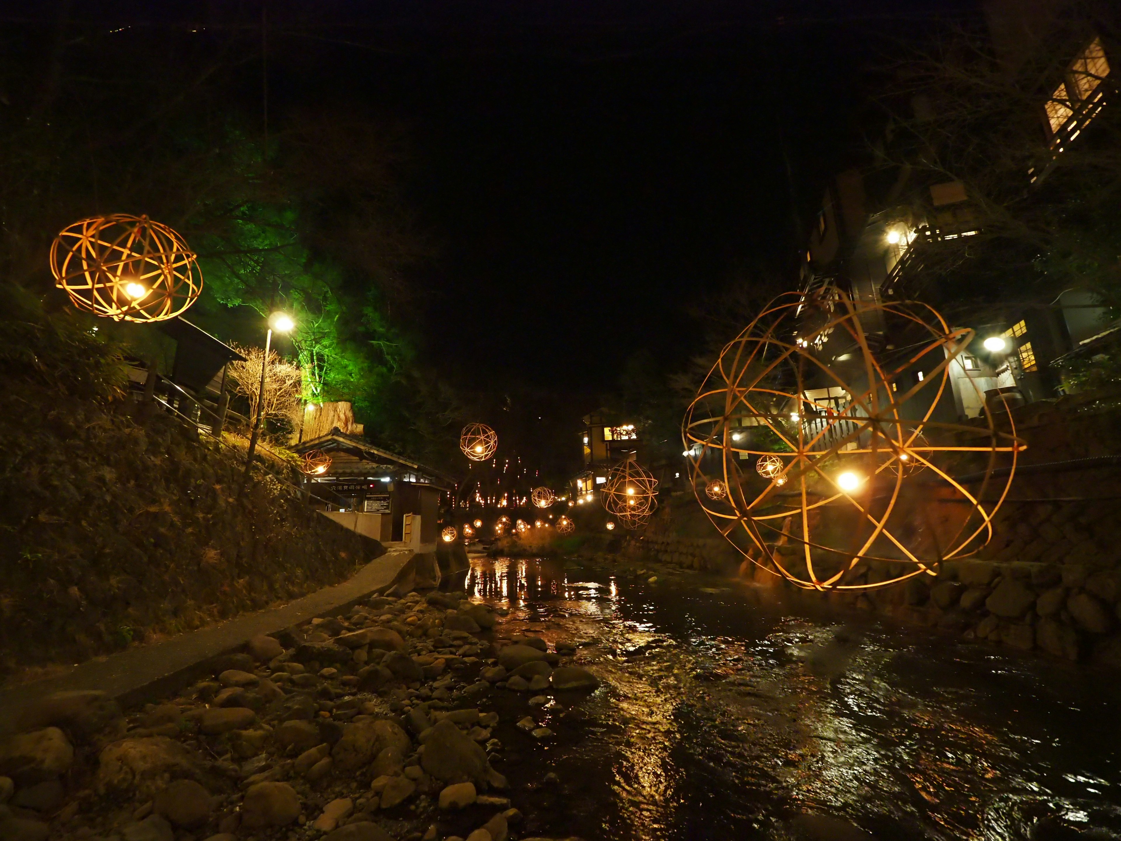 Vista escénica de decoraciones esféricas iluminadas a lo largo de un río por la noche