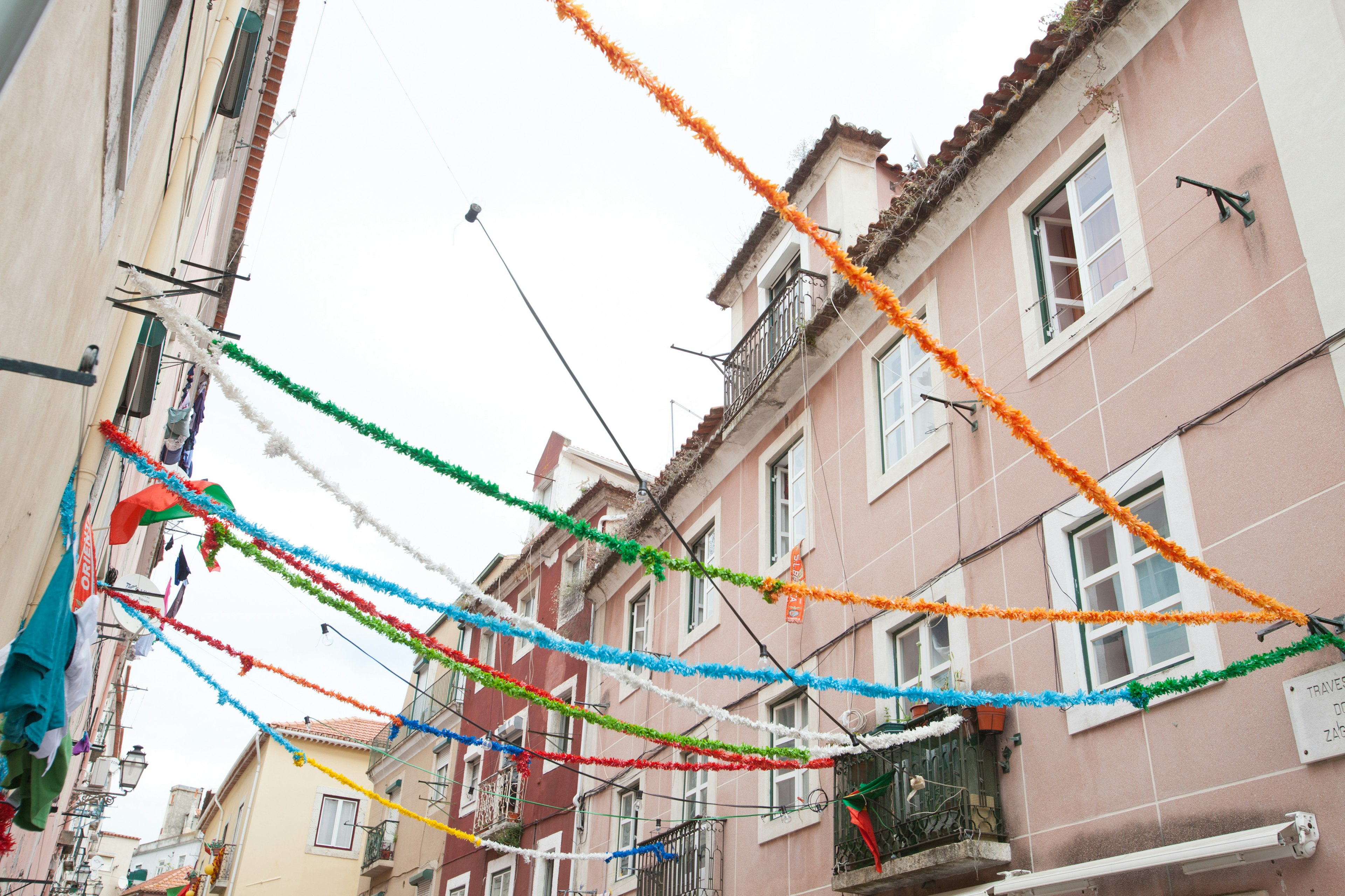 Decoraciones coloridas colgadas sobre una calle estrecha con edificios en tonos pastel