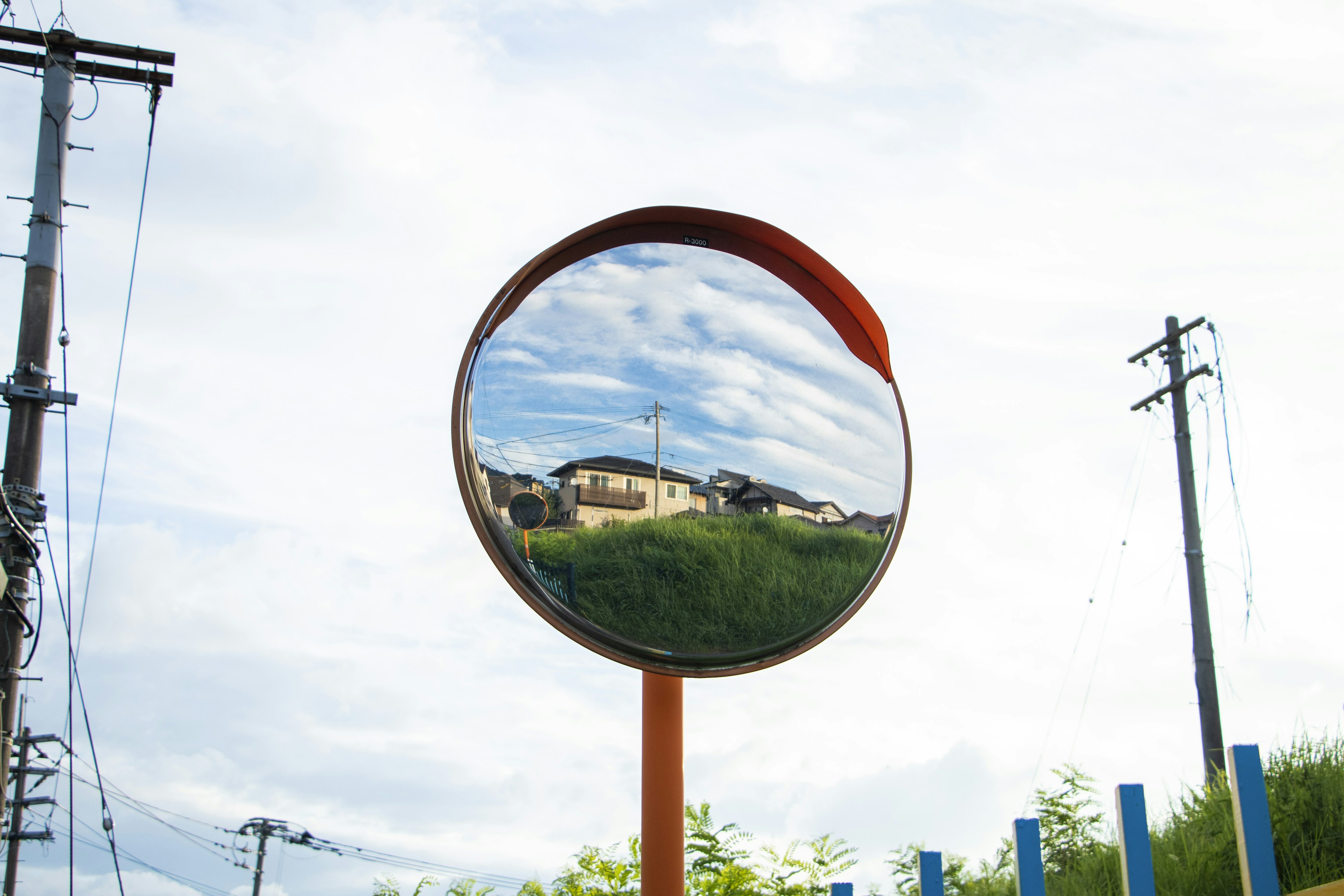 Espejo reflectante que muestra casas y cielo