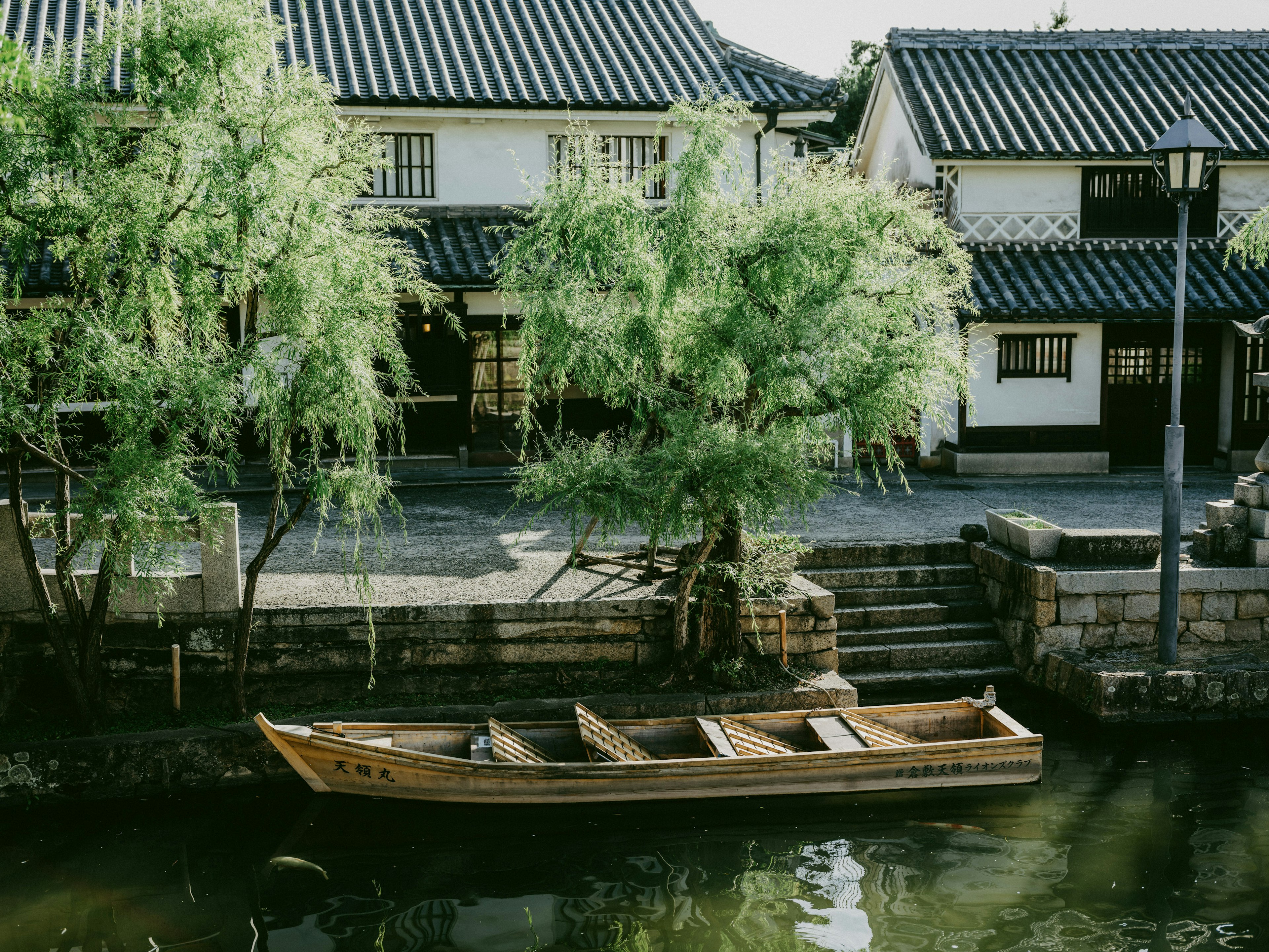 宁静的河边场景，木船停靠在传统日本房屋旁边