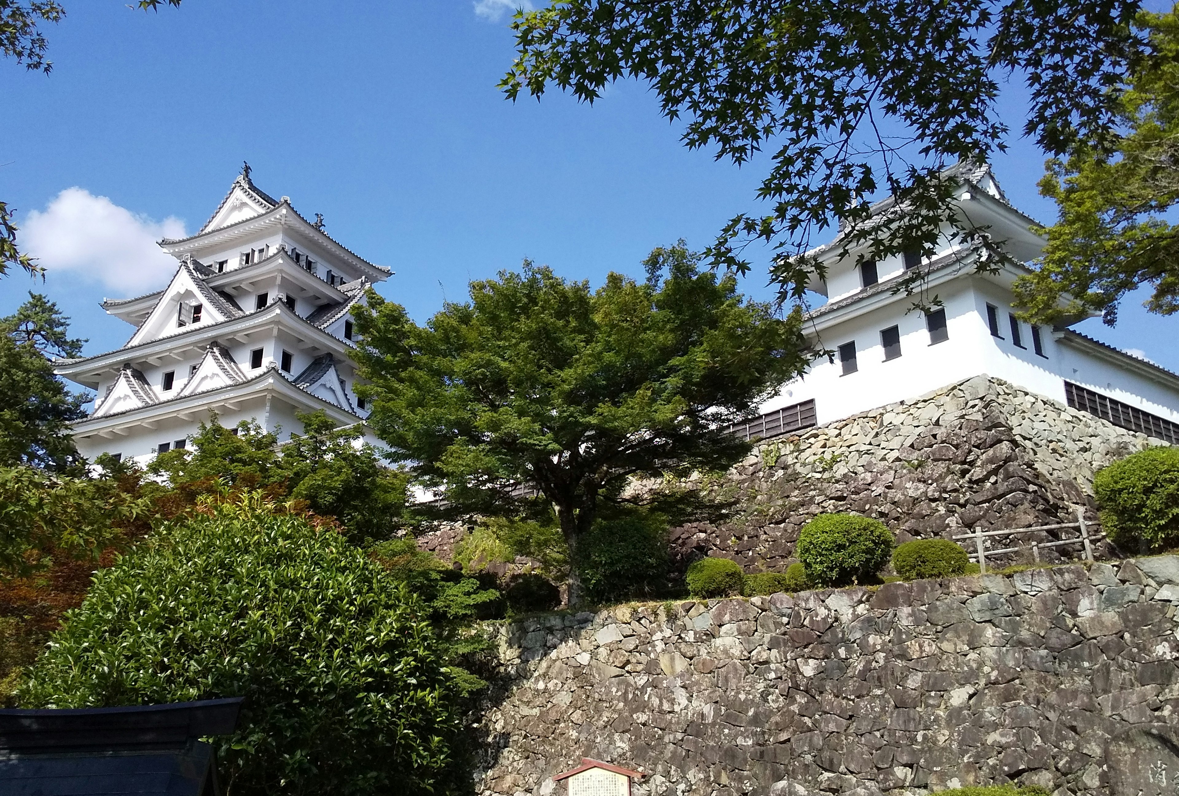 A view of a white castle with trees and stone walls