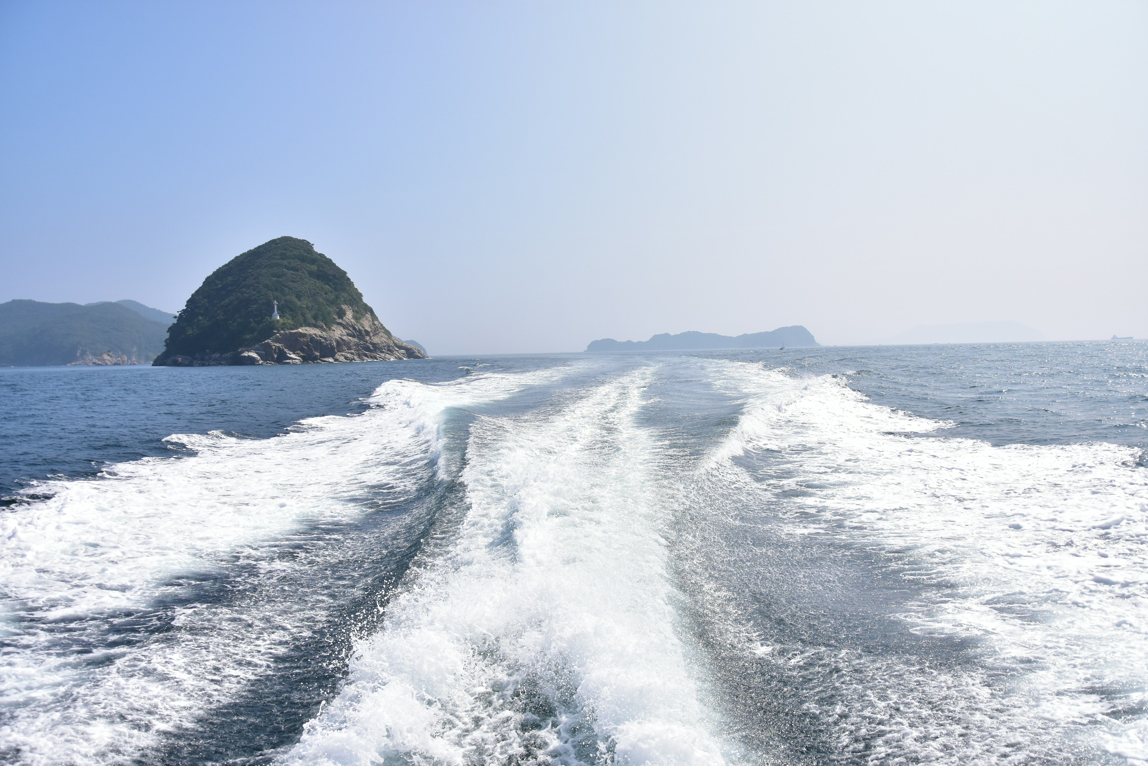 Sillage de bateau sur l'océan avec des îles au loin