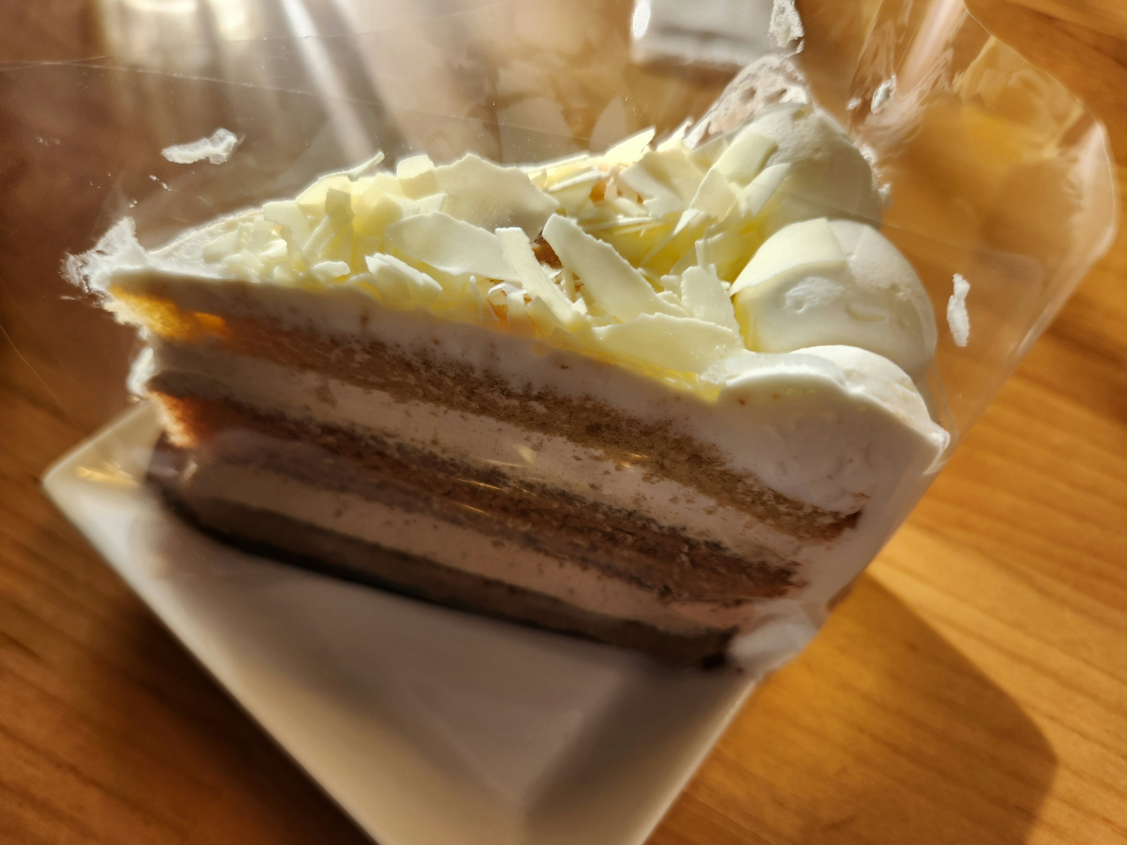 Une tranche de gâteau en couches avec de la crème et du chocolat blanc sur le dessus