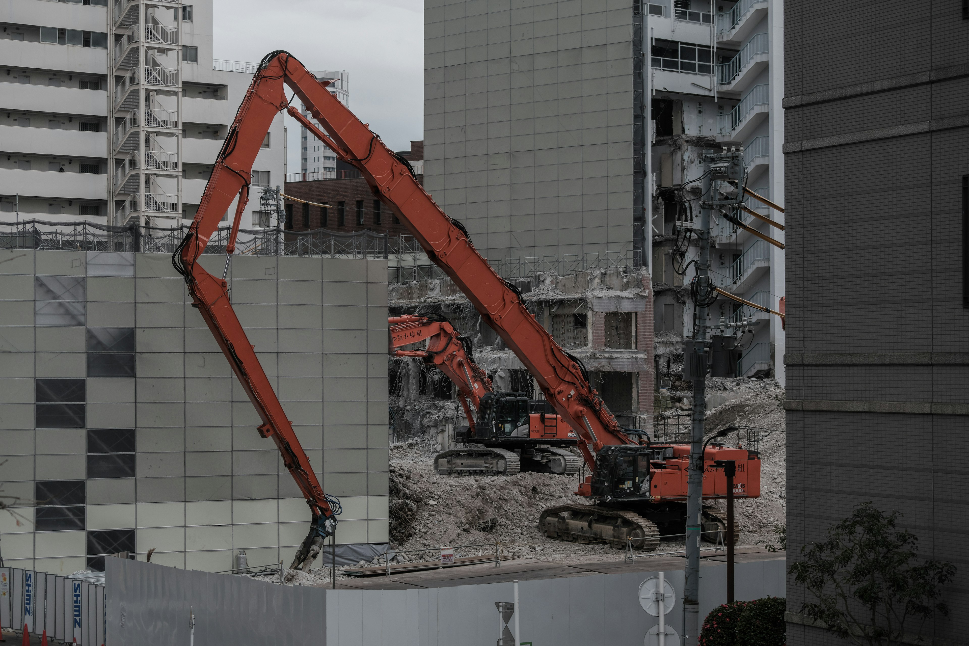 Bauplatz mit orangefarbener Maschine und Trümmern von abgerissenen Gebäuden