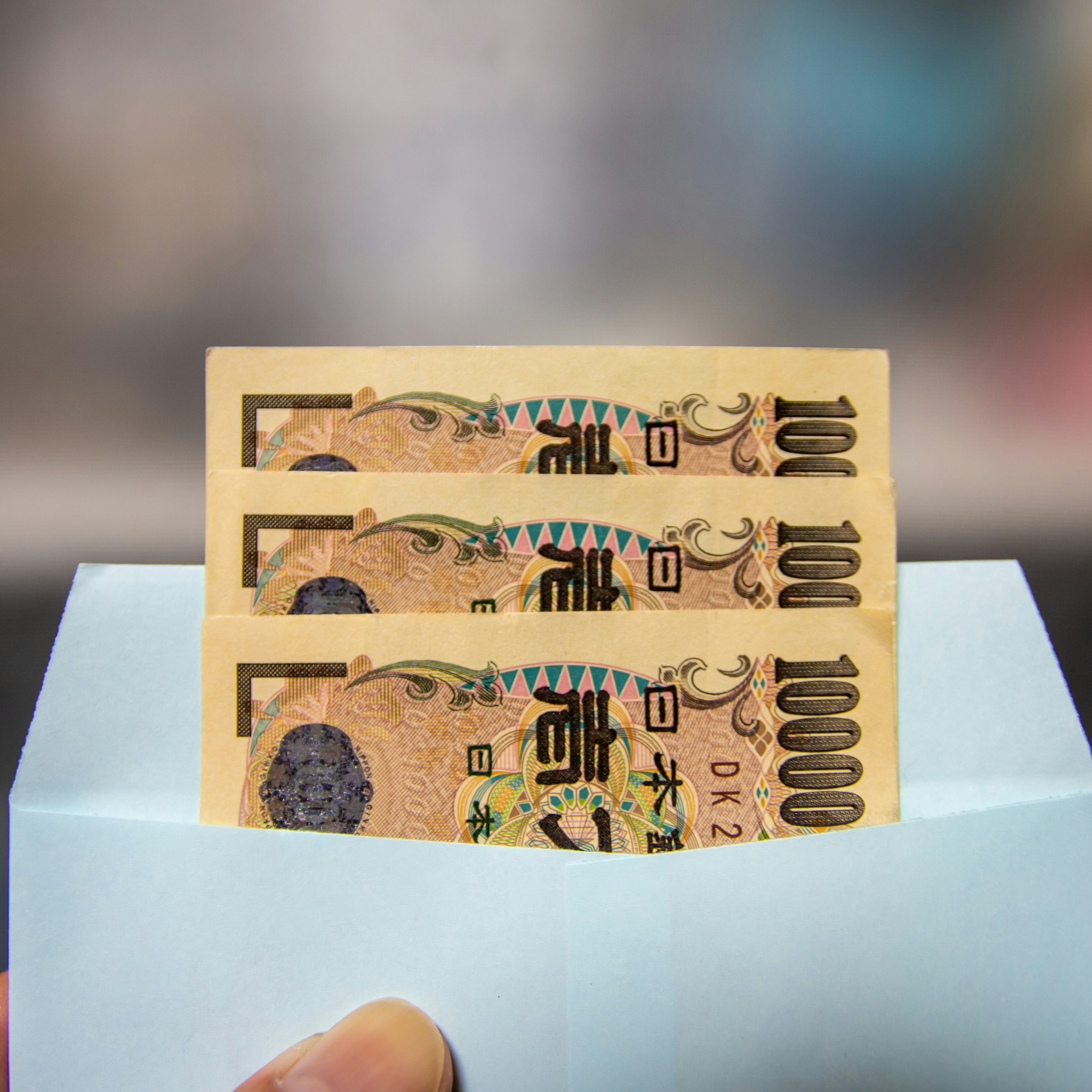 Three 1000 yen bills partially visible in a blue envelope