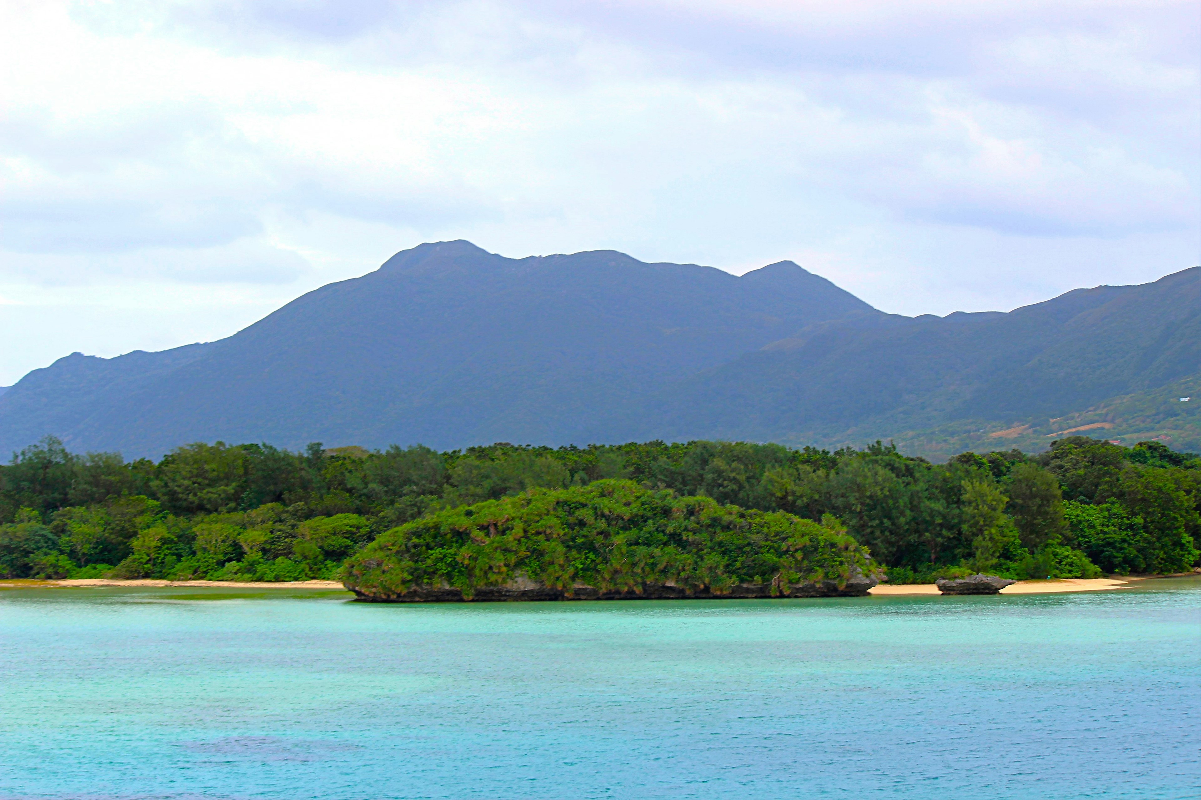 ทิวทัศน์ที่สวยงามของทะเลสีเขียวมรกตพร้อมเกาะเขียวชอุ่มและภูเขา