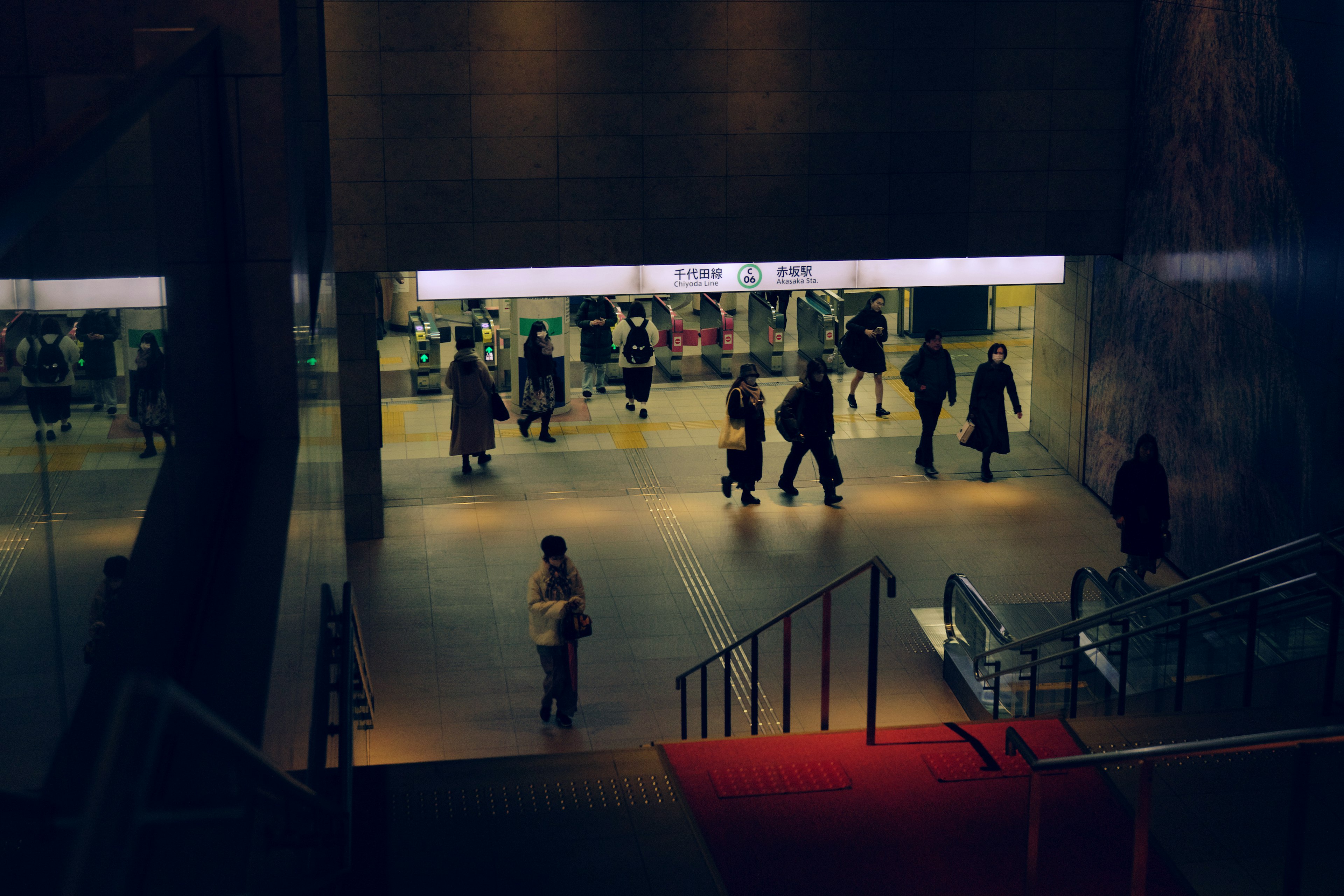 Persone che camminano in un'entrata di stazione della metropolitana poco illuminata