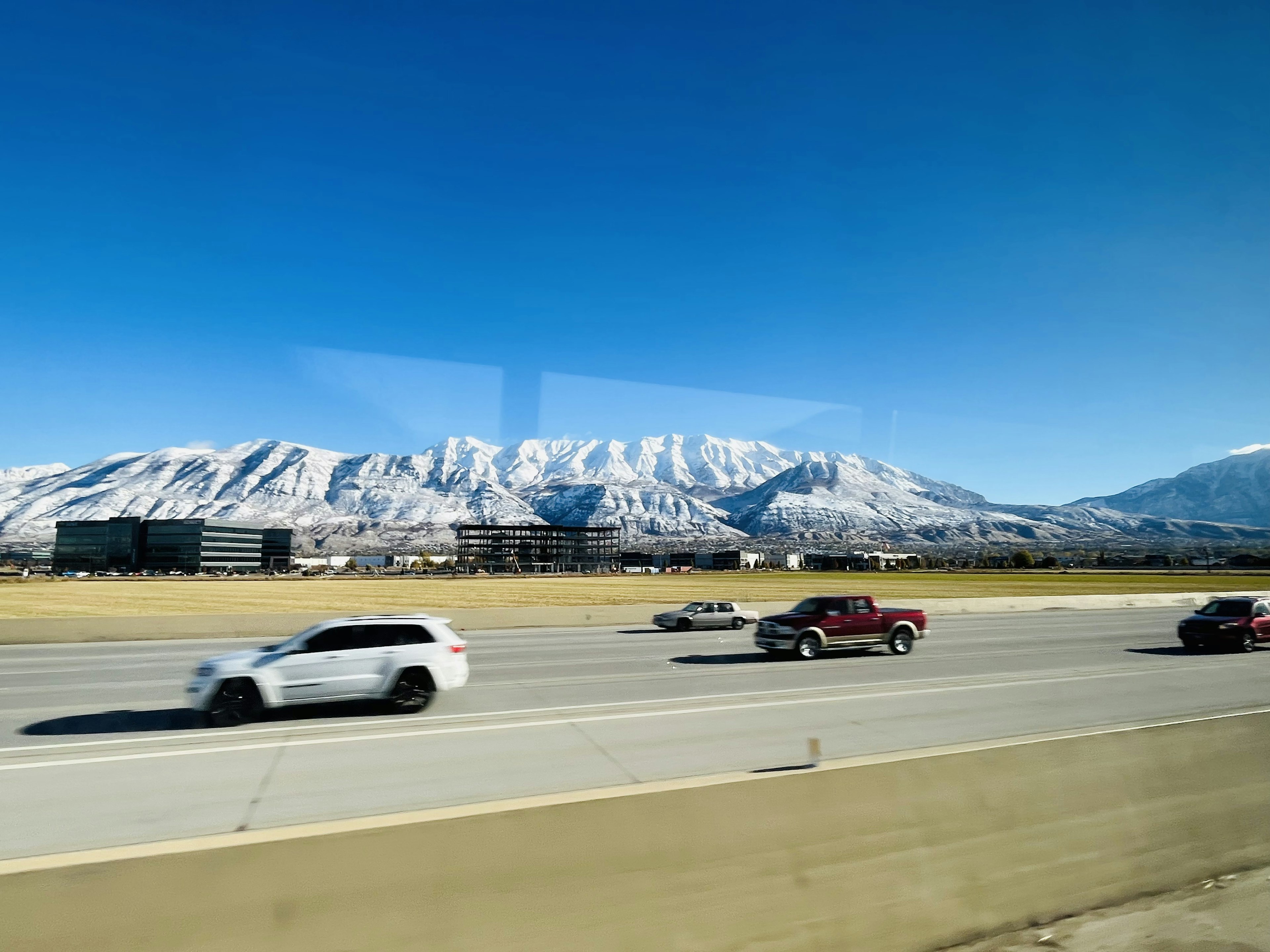 車輛在公路上行駛，背景是被雪覆蓋的山脈