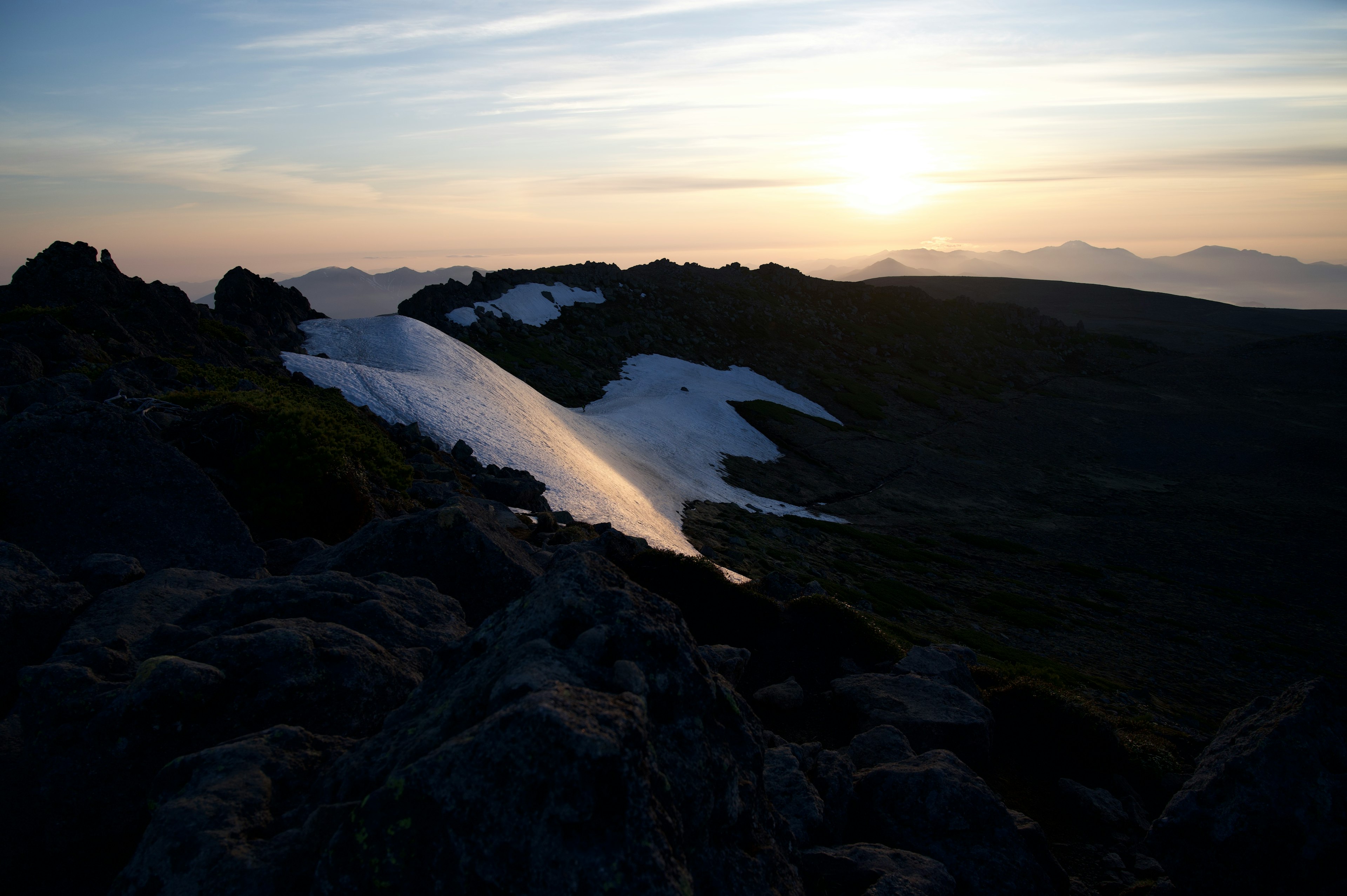 Paesaggio montano con neve che si scioglie e luce del tramonto