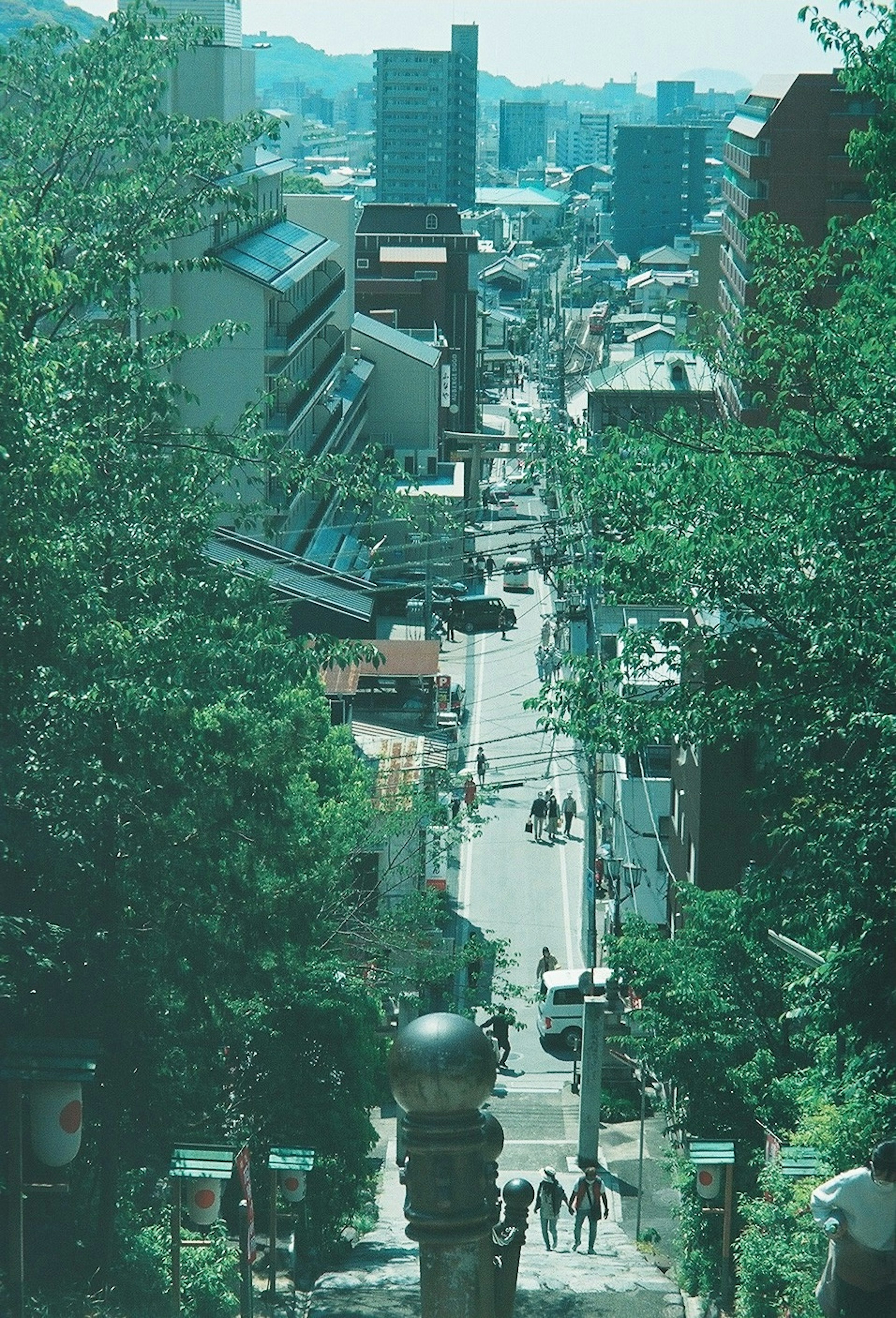 A scenic view of a sloped street lined with trees and buildings