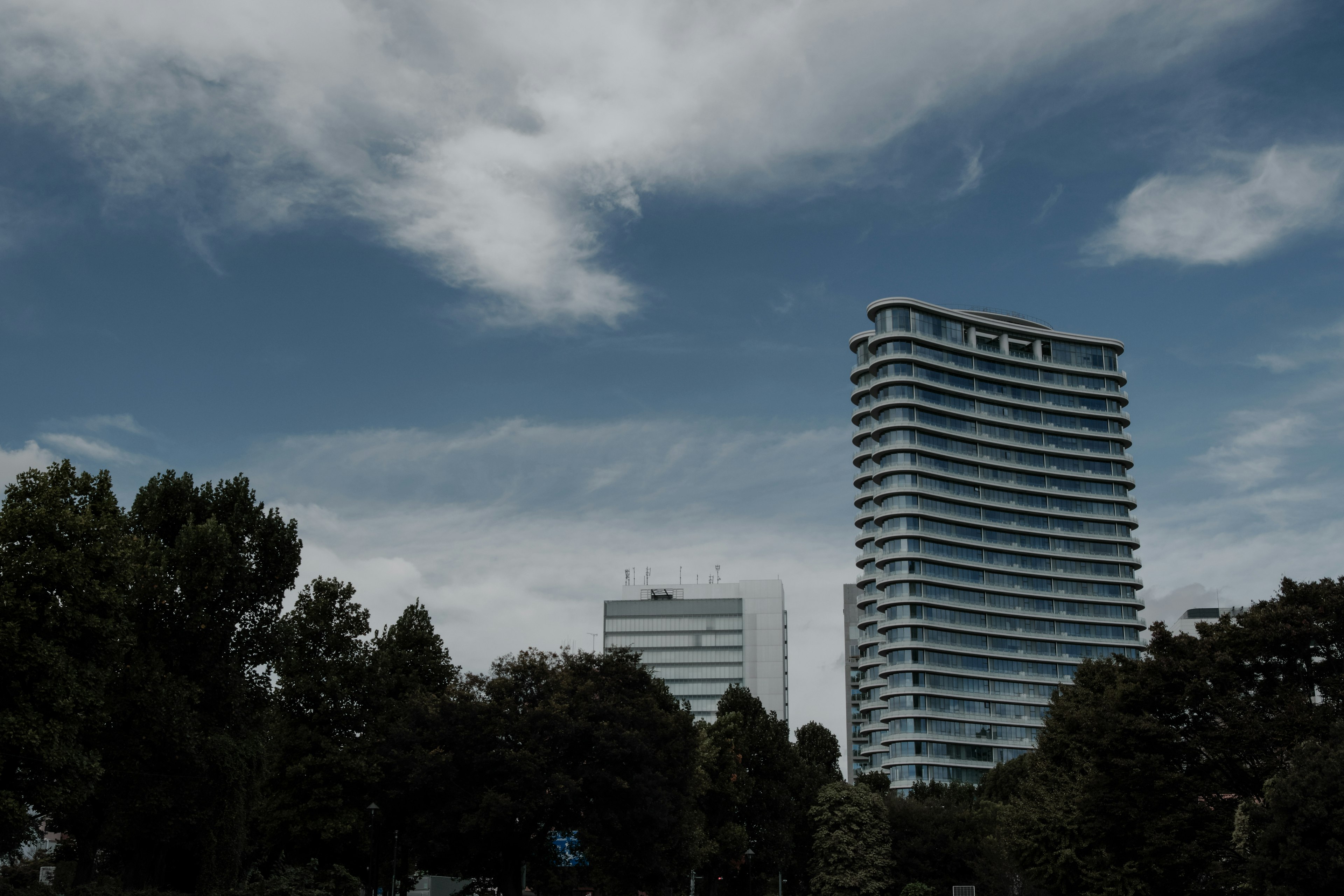 Modern buildings under a blue sky with clouds and surrounding greenery