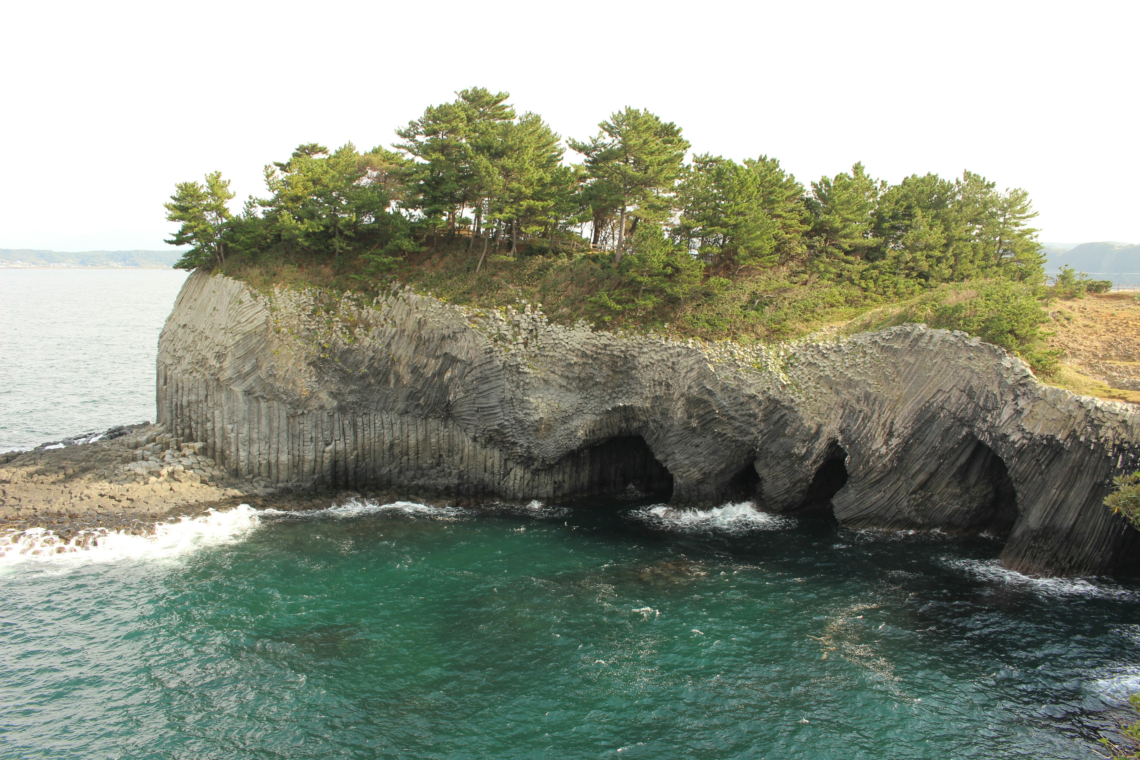 綠色小島與岩石懸崖及海洋波浪的風景