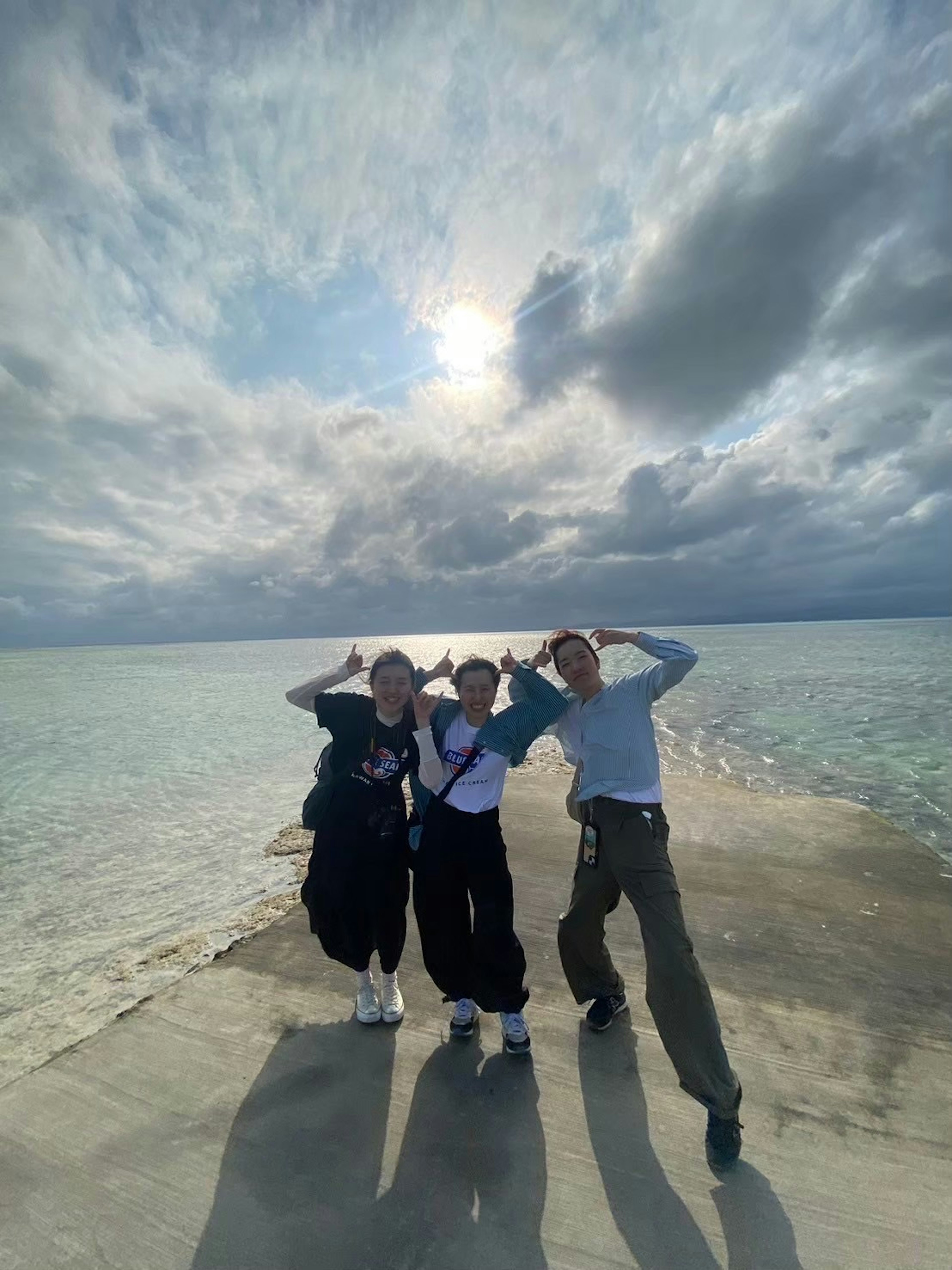 Three friends posing joyfully on a pier over the sea