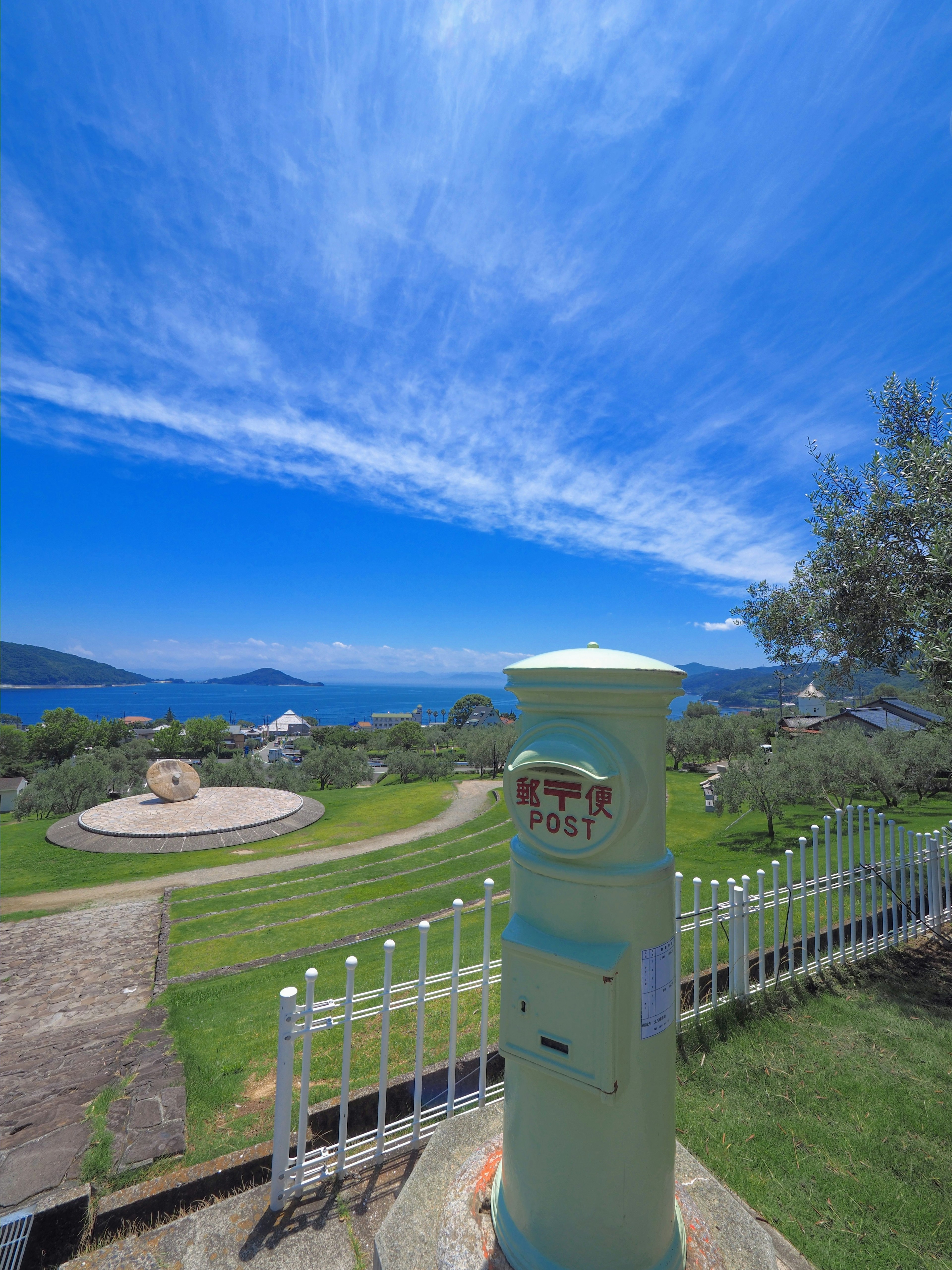 Postbox under a blue sky with a scenic ocean view