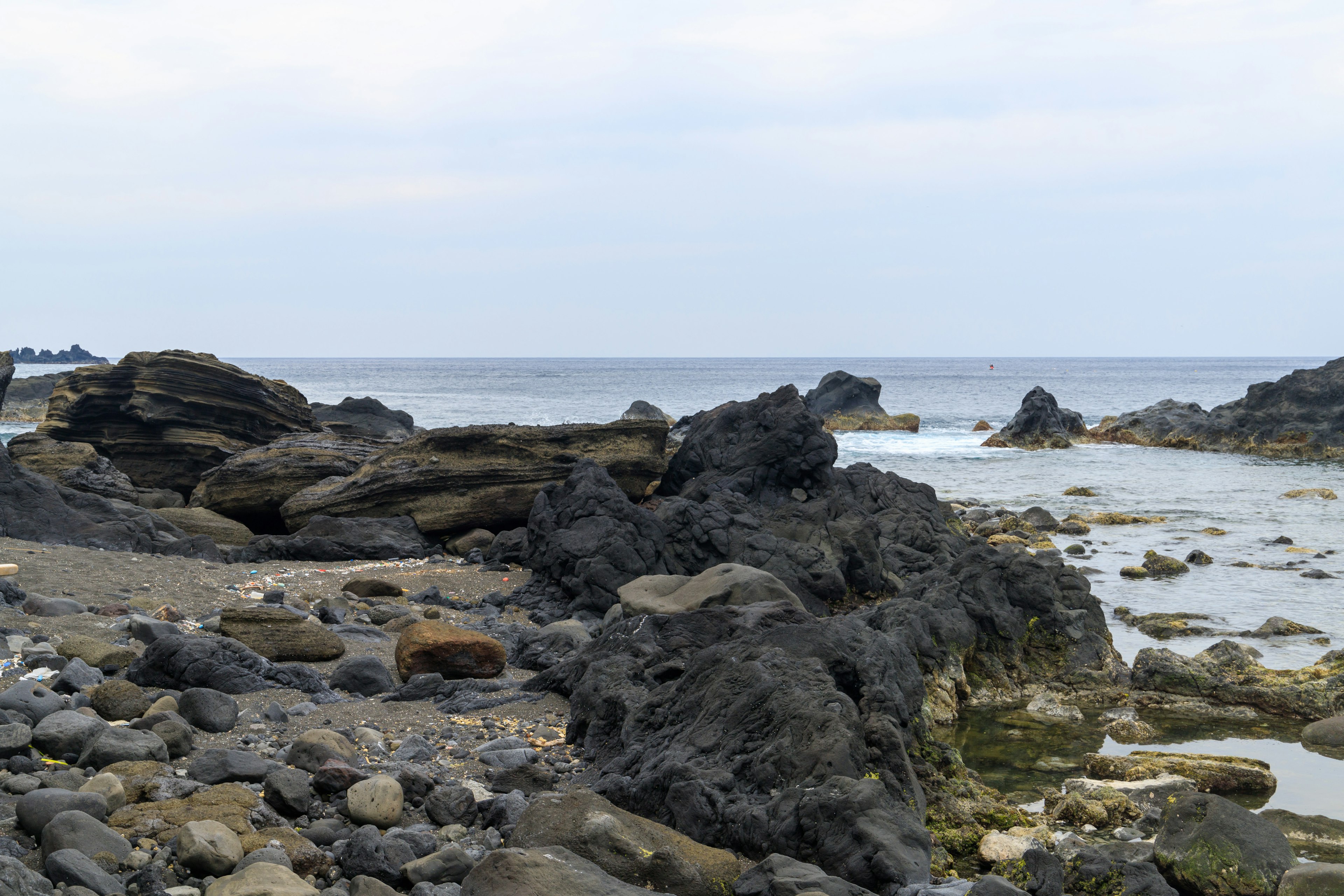 Rocky shoreline with calm sea and cloudy sky