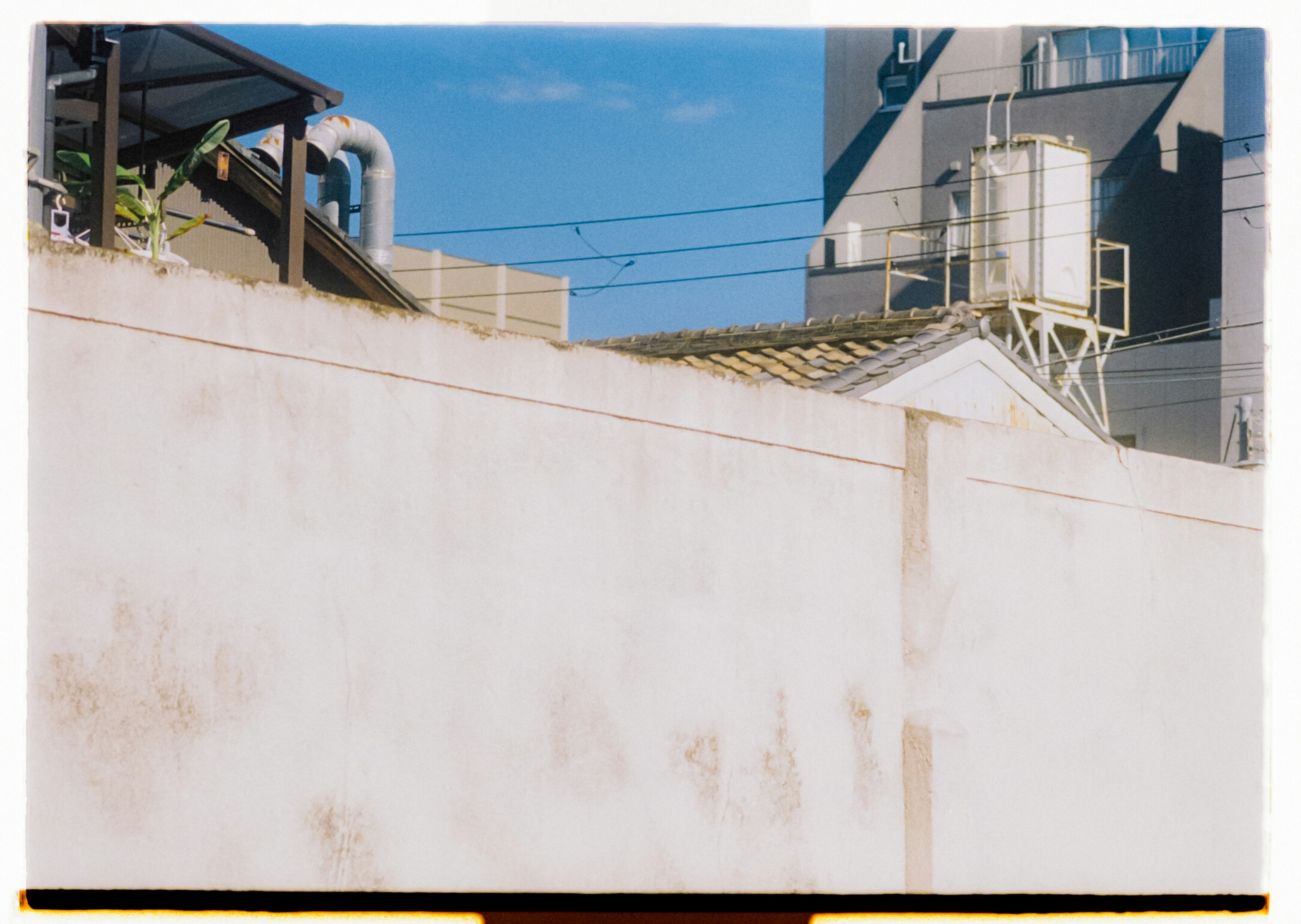 White wall with blue sky industrial structures in background