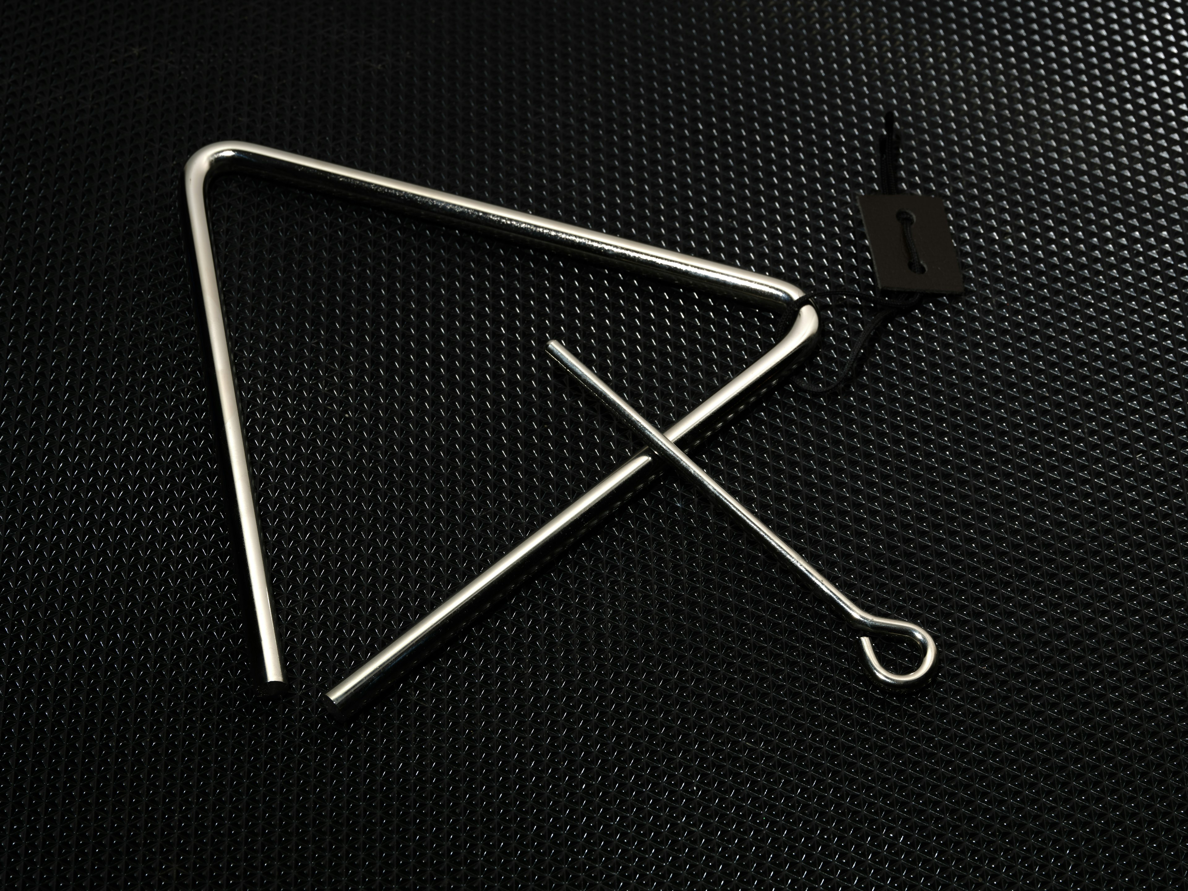 Metal triangle musical instrument with a stick on a black background