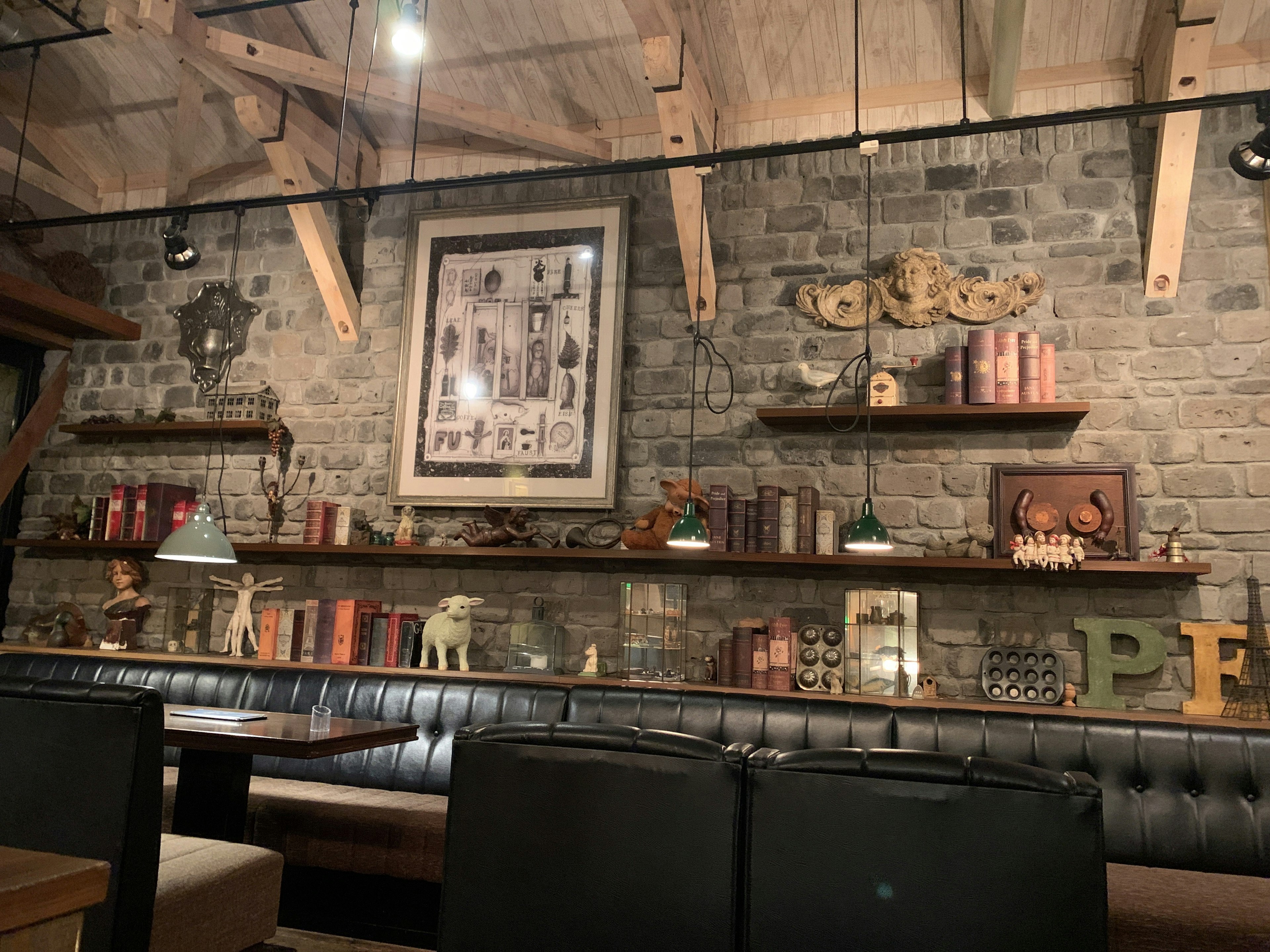 Interior of a restaurant featuring wooden beams and stone walls Shelves filled with books and decorative items