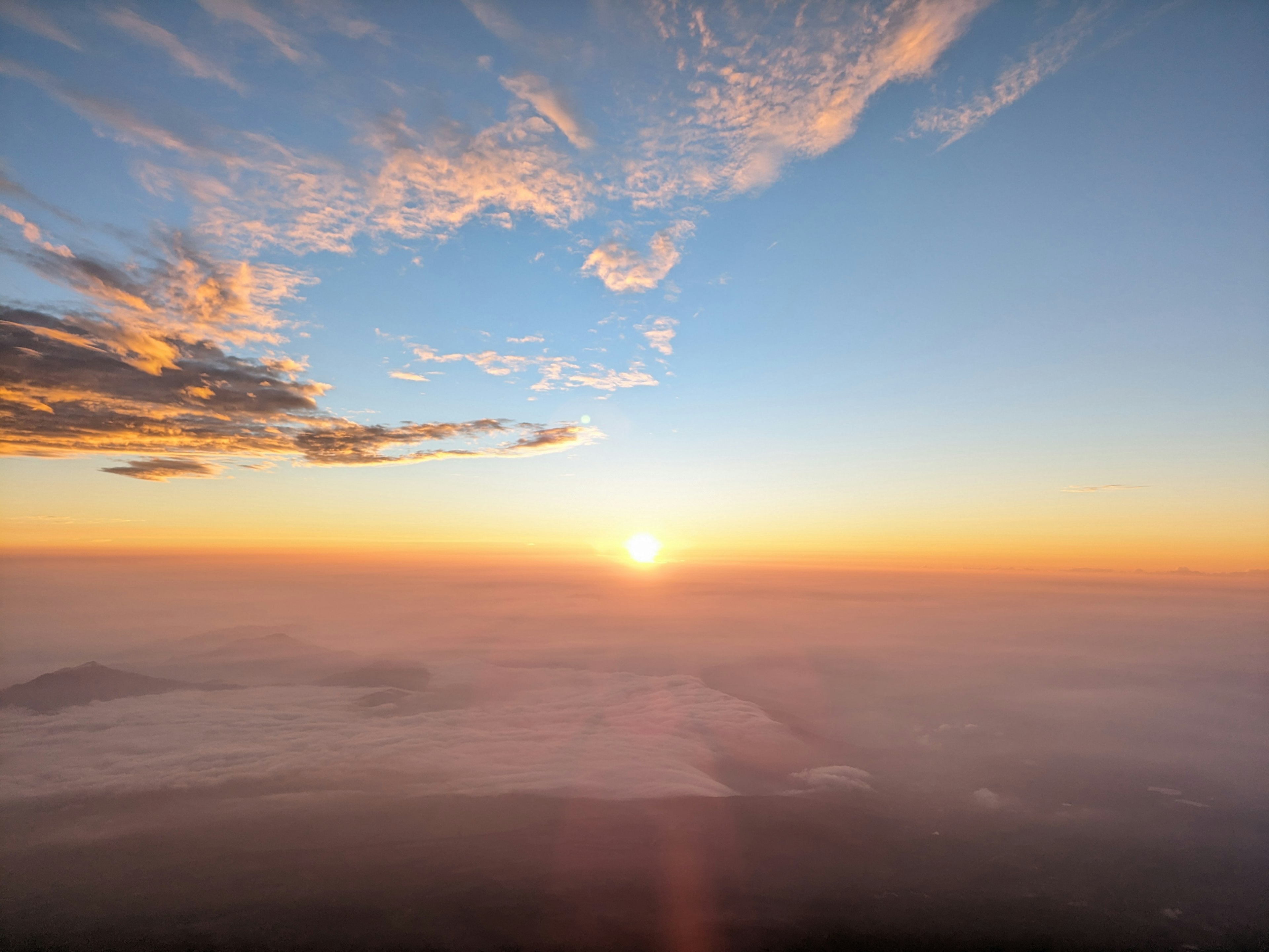 Bellissimo paesaggio all'alba con nuvole e cielo blu caratterizzato da una luce arancione che si diffonde all'orizzonte