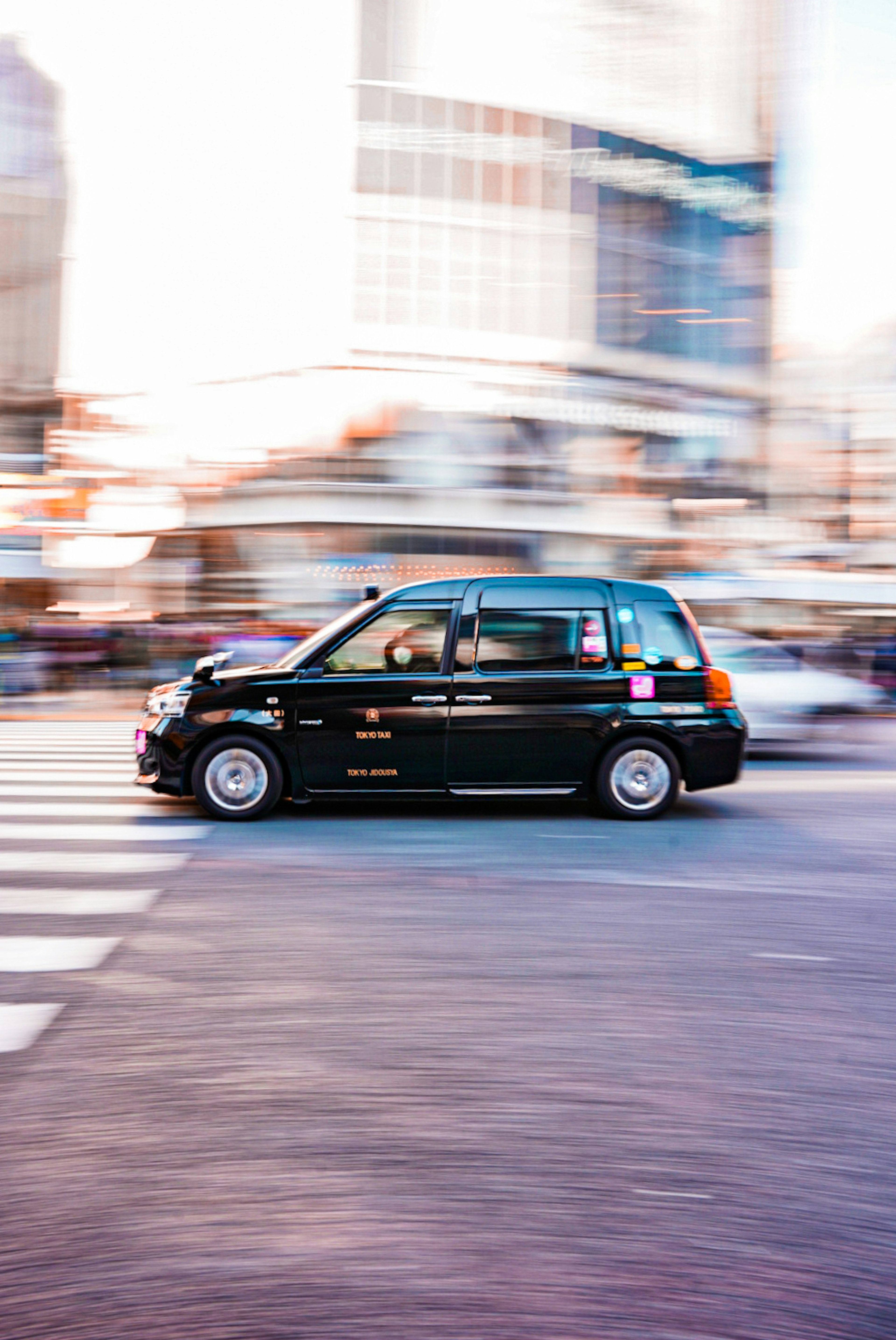 Schwarzes Taxi fährt durch eine belebte Kreuzung mit Bewegungsunschärfe