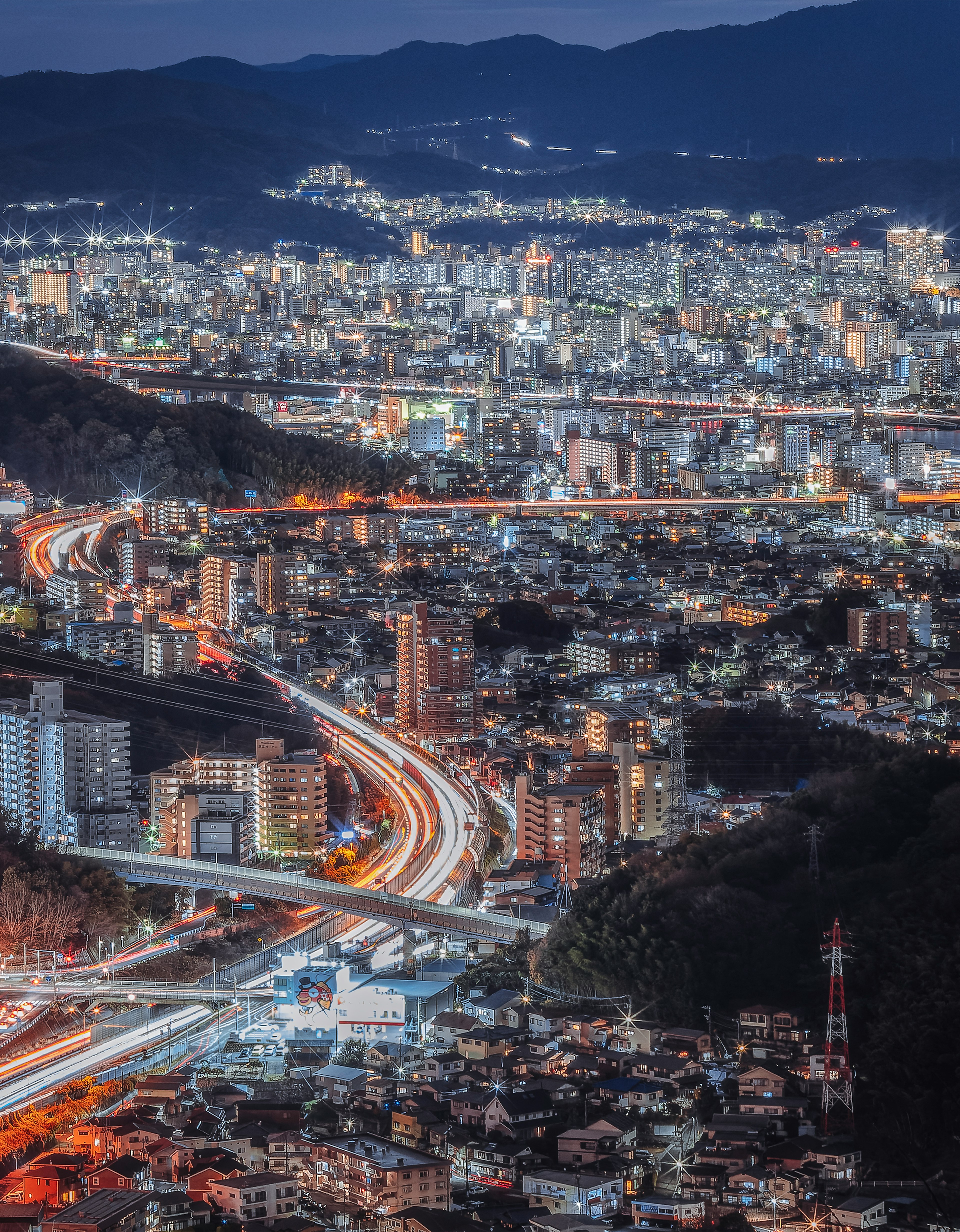 Vue panoramique époustouflante d'une ville la nuit avec des gratte-ciels illuminés et des routes sinueuses