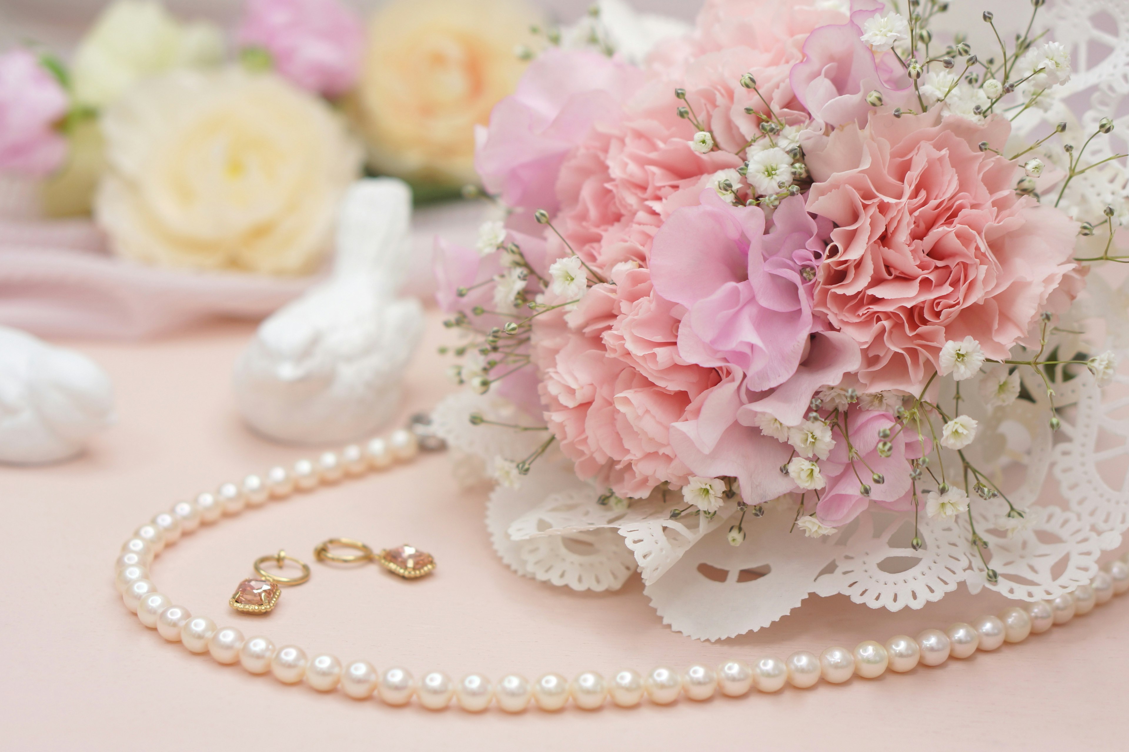 Un bel arrangement avec un bouquet rose et un collier de perles