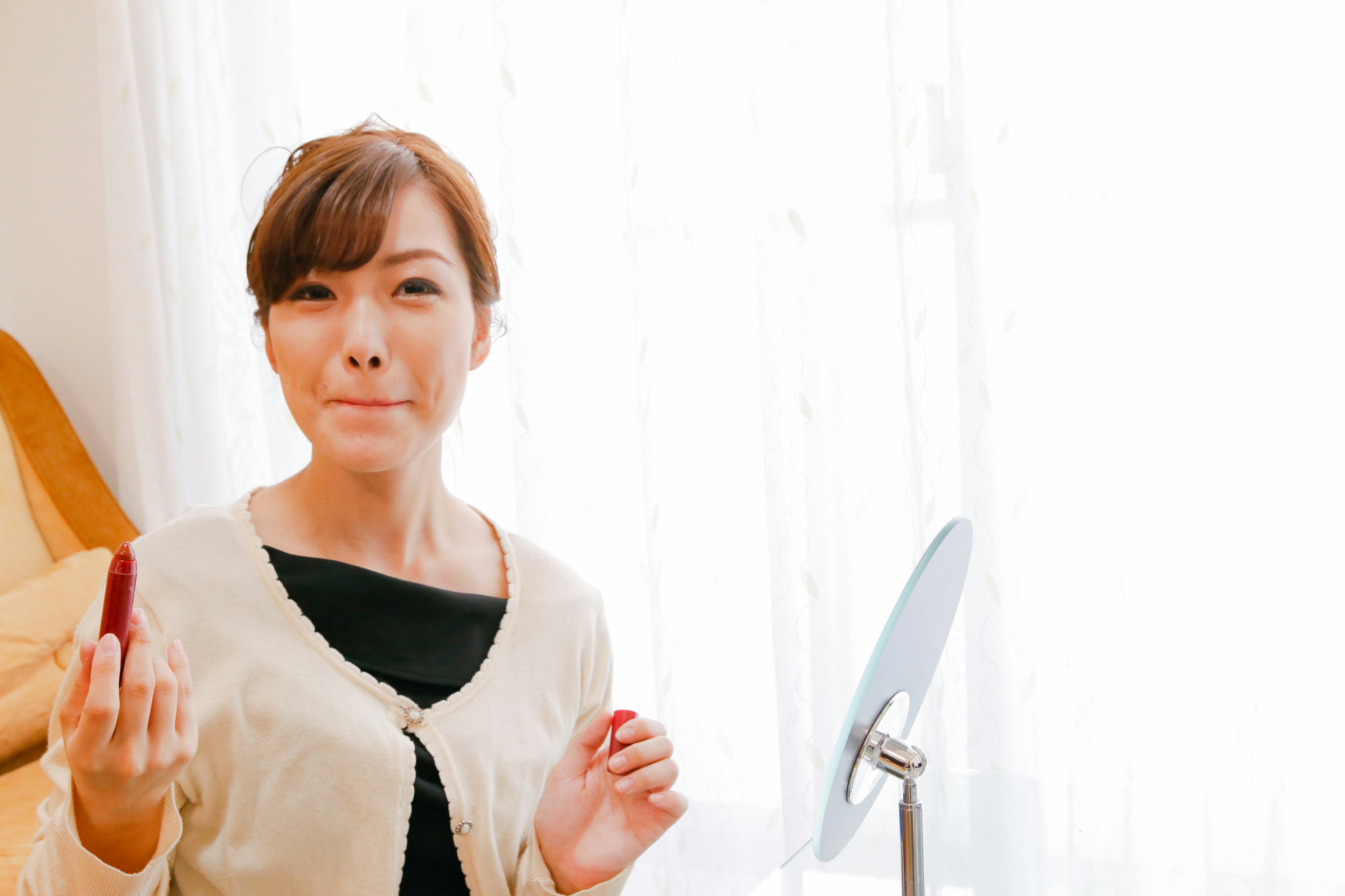 A woman holding lipstick and smiling Bright natural light from the window