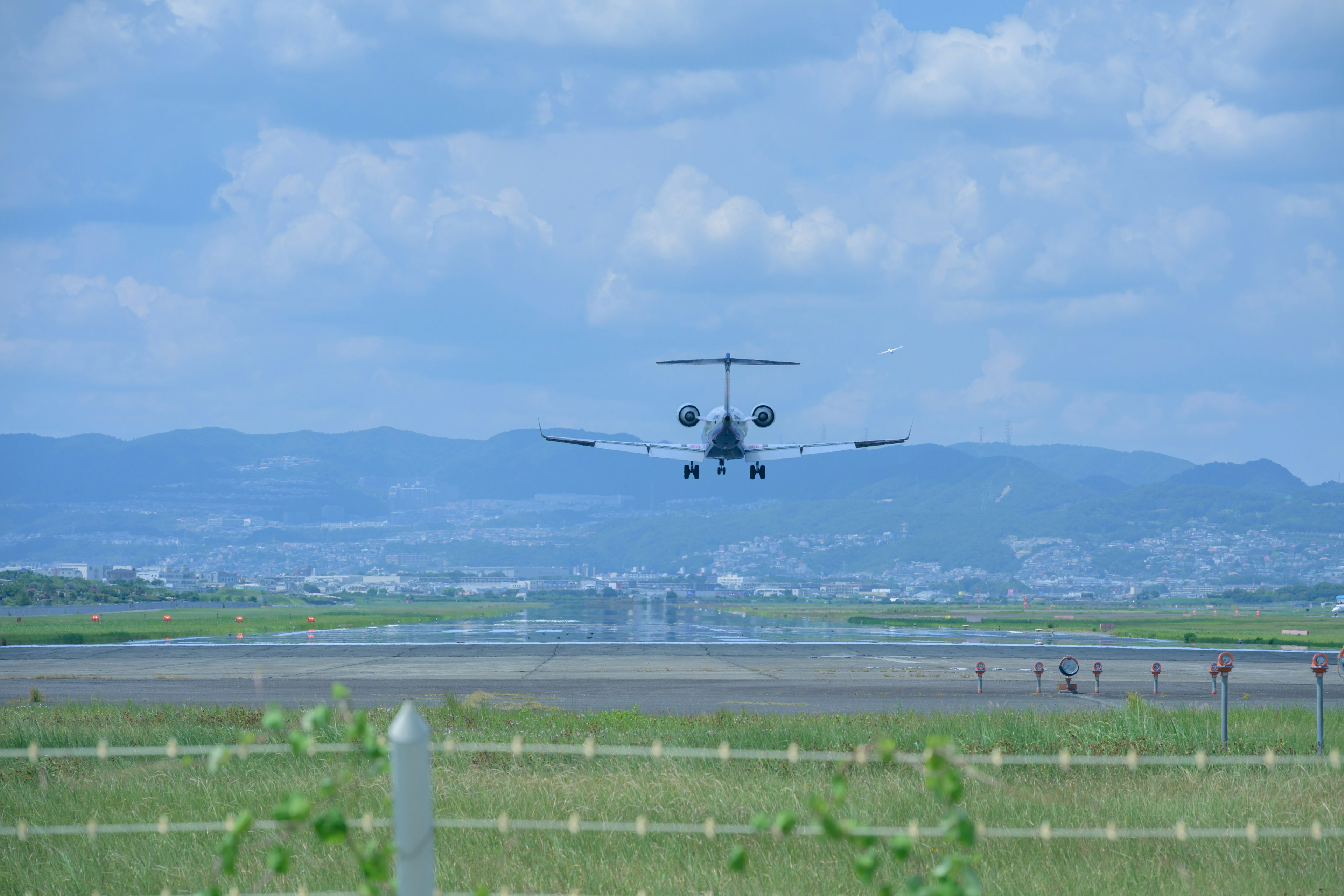 Un aereo in atterraggio sotto un cielo blu con vasta erba verde