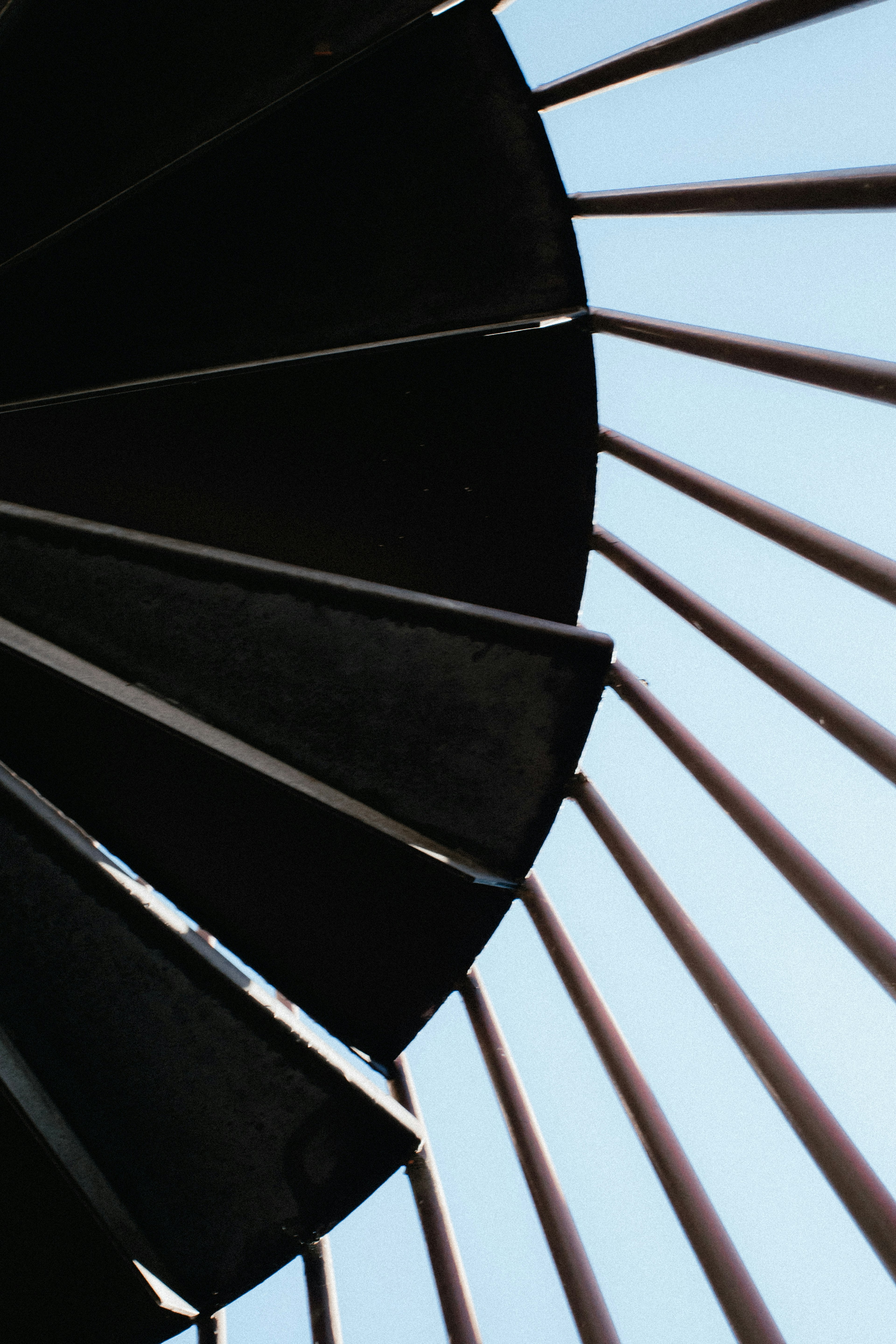 Spiraltreppe mit schwarzen Stufen und blauem Himmel