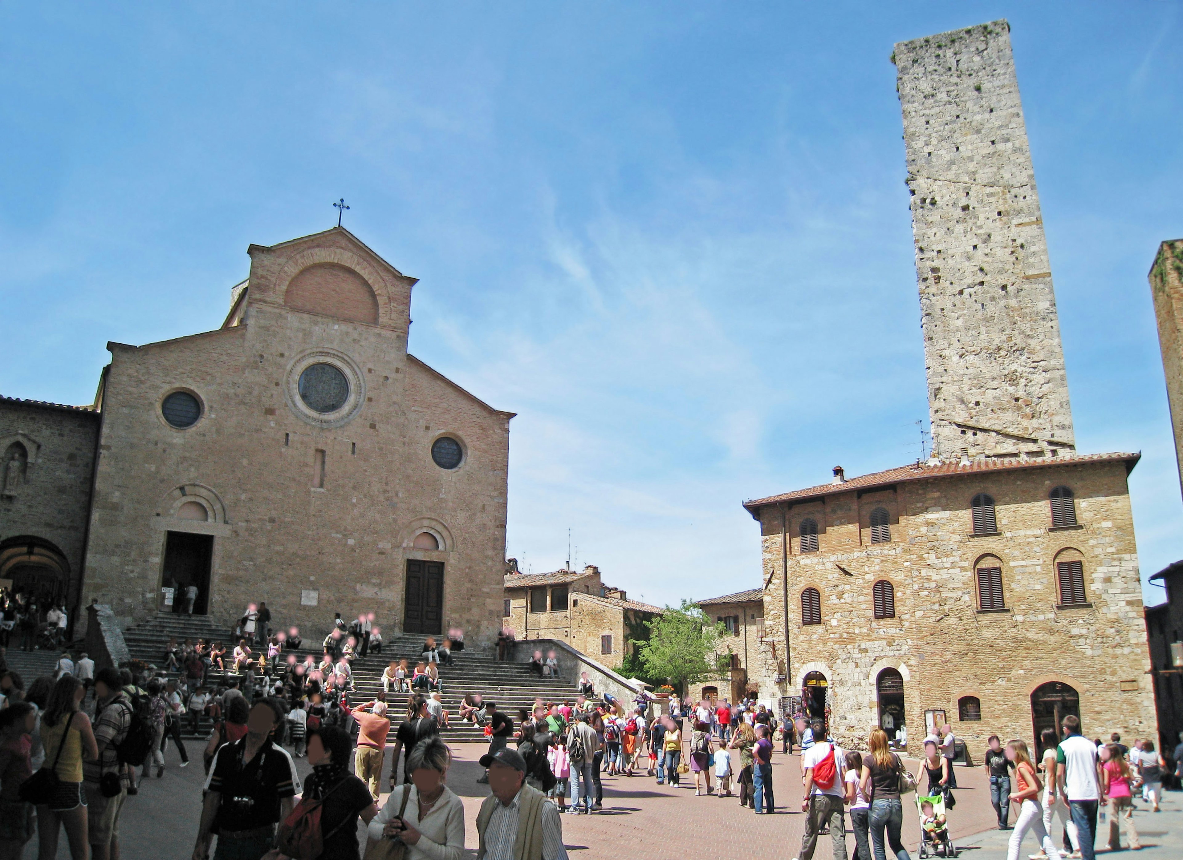 Iglesia histórica y torre en una plaza concurrida llena de personas