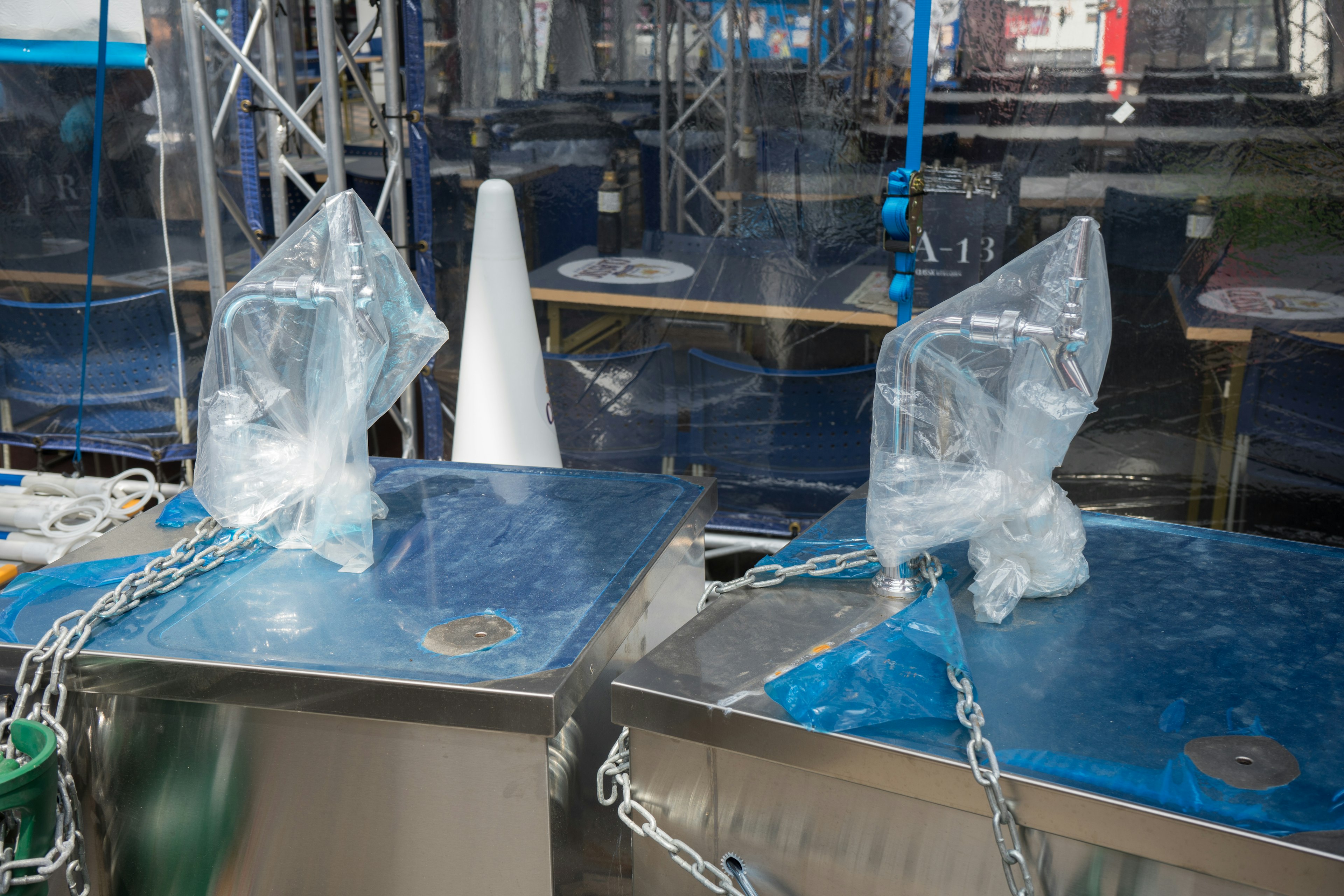 Two blocks of ice wrapped in transparent plastic bags placed on metallic tables