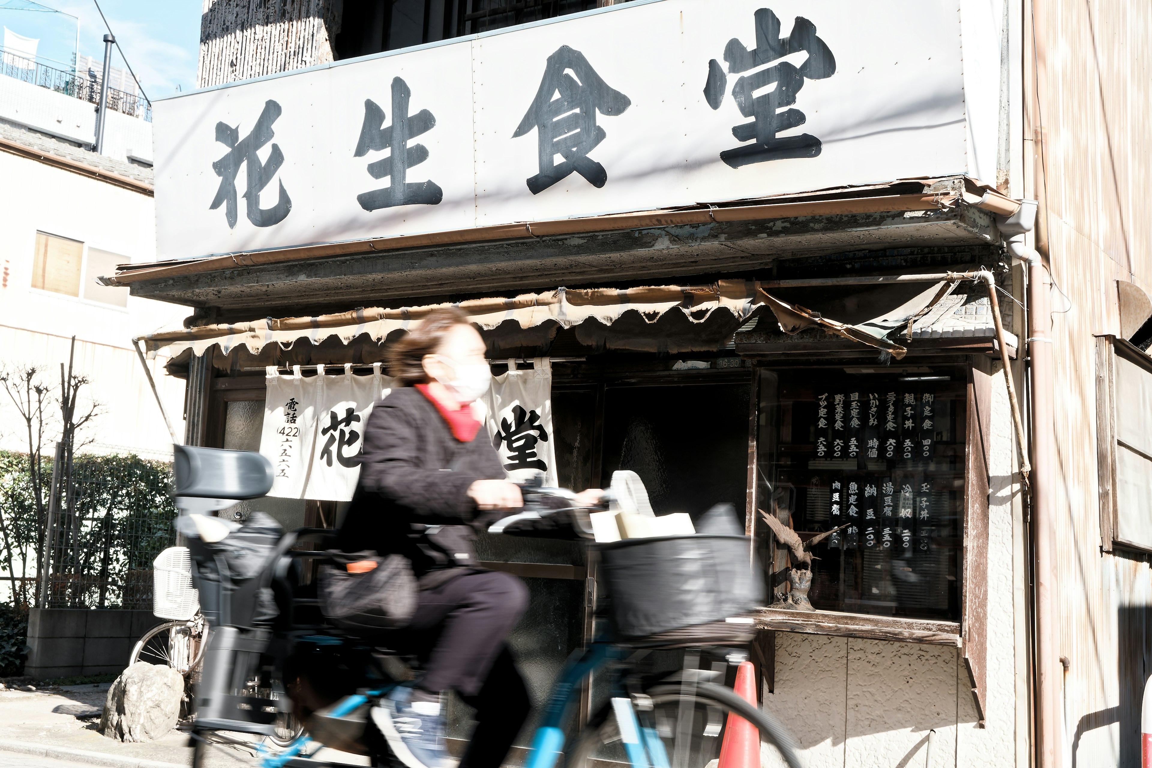 古い食堂の外観と自転車に乗った人物