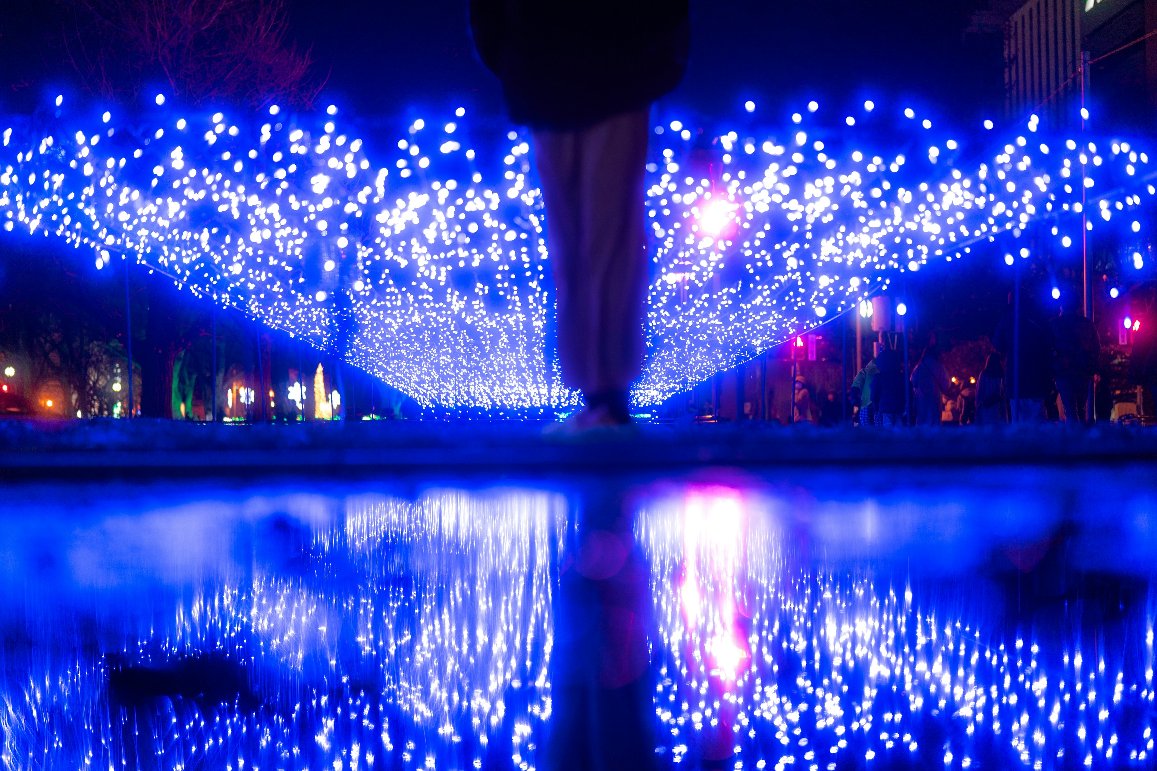 Personne marchant sous des lumières bleues avec des reflets dans une flaque