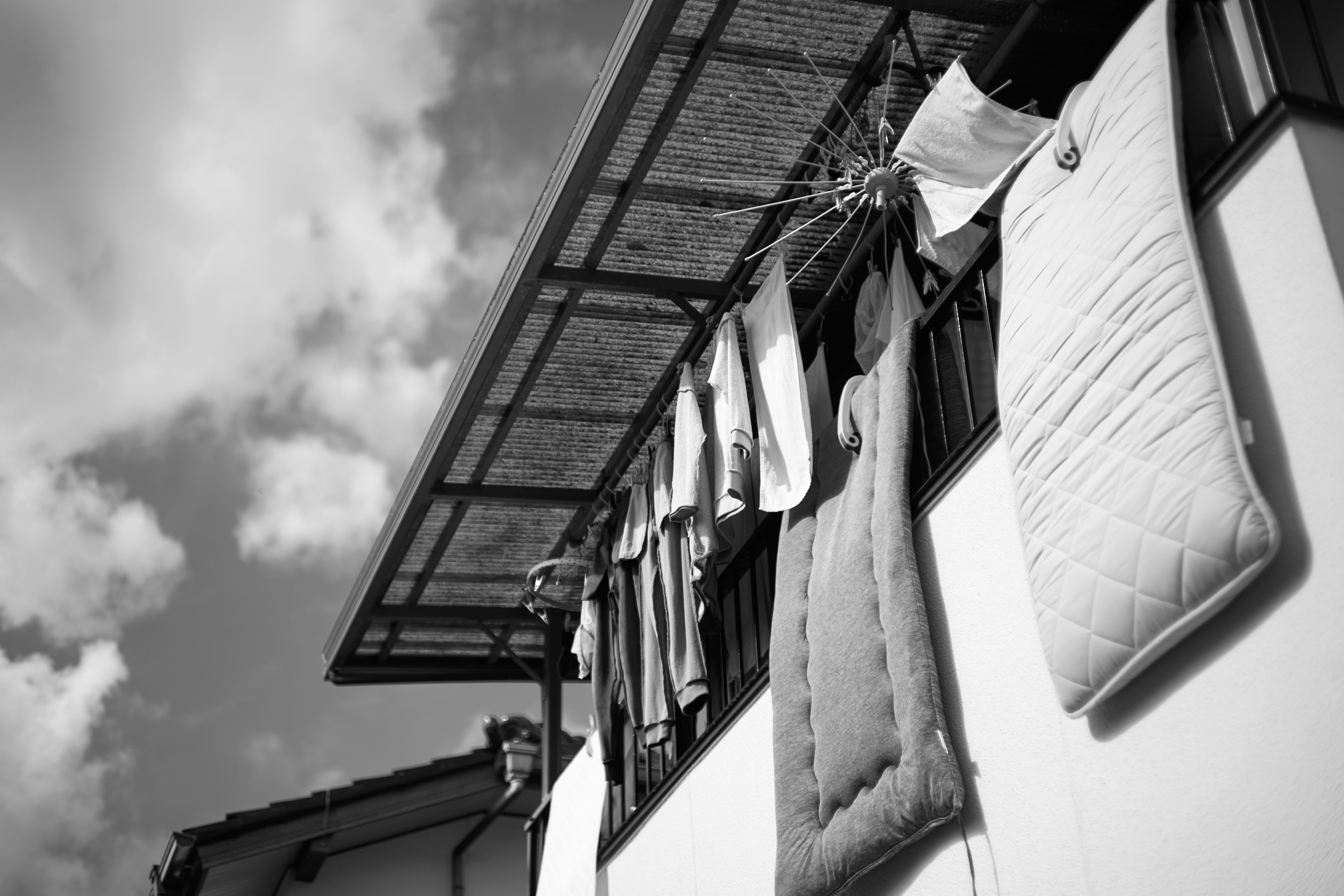 Black and white image of bedding and towels hanging on a rooftop