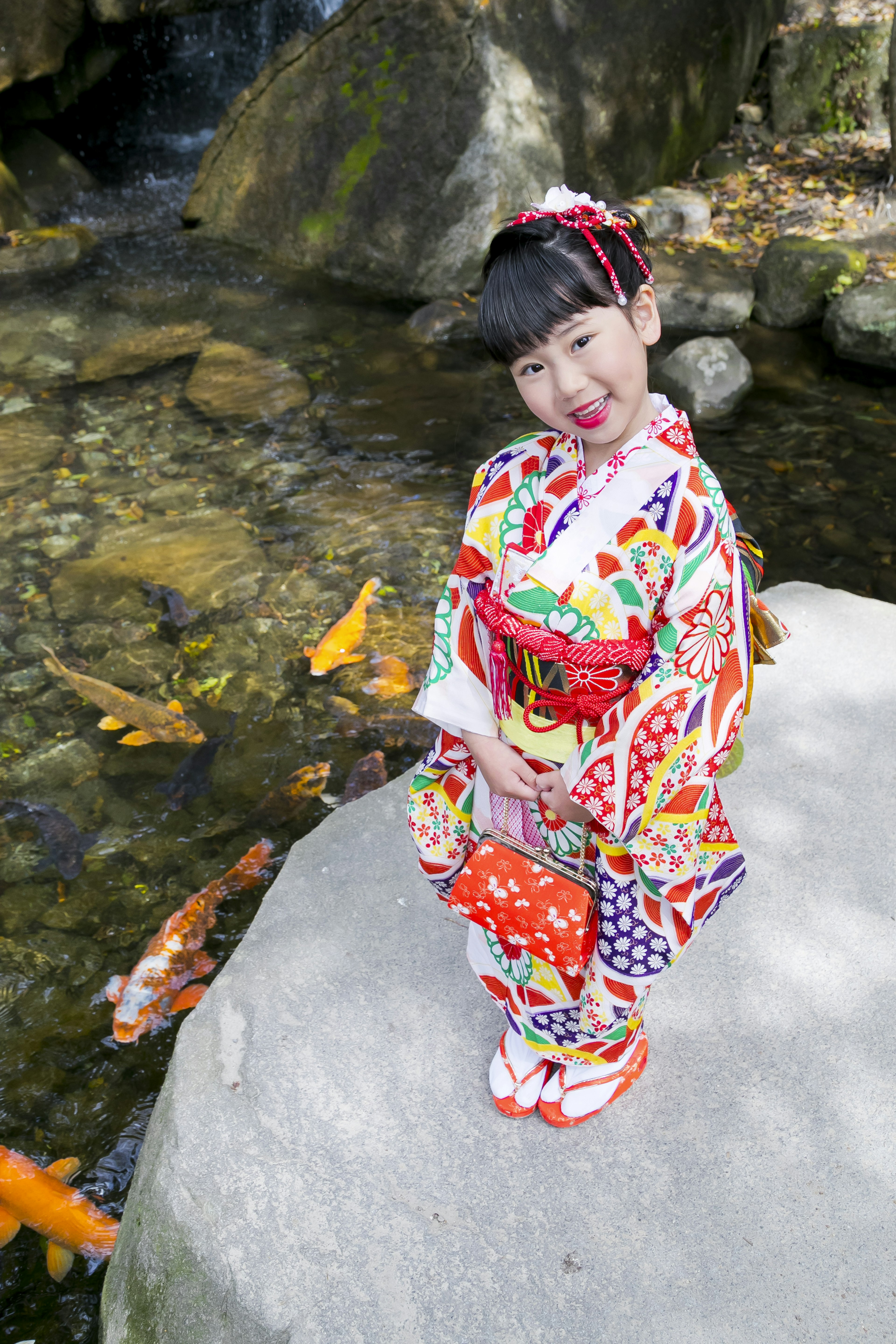 Anak yang berpose dengan kimono berwarna-warni di tepi aliran