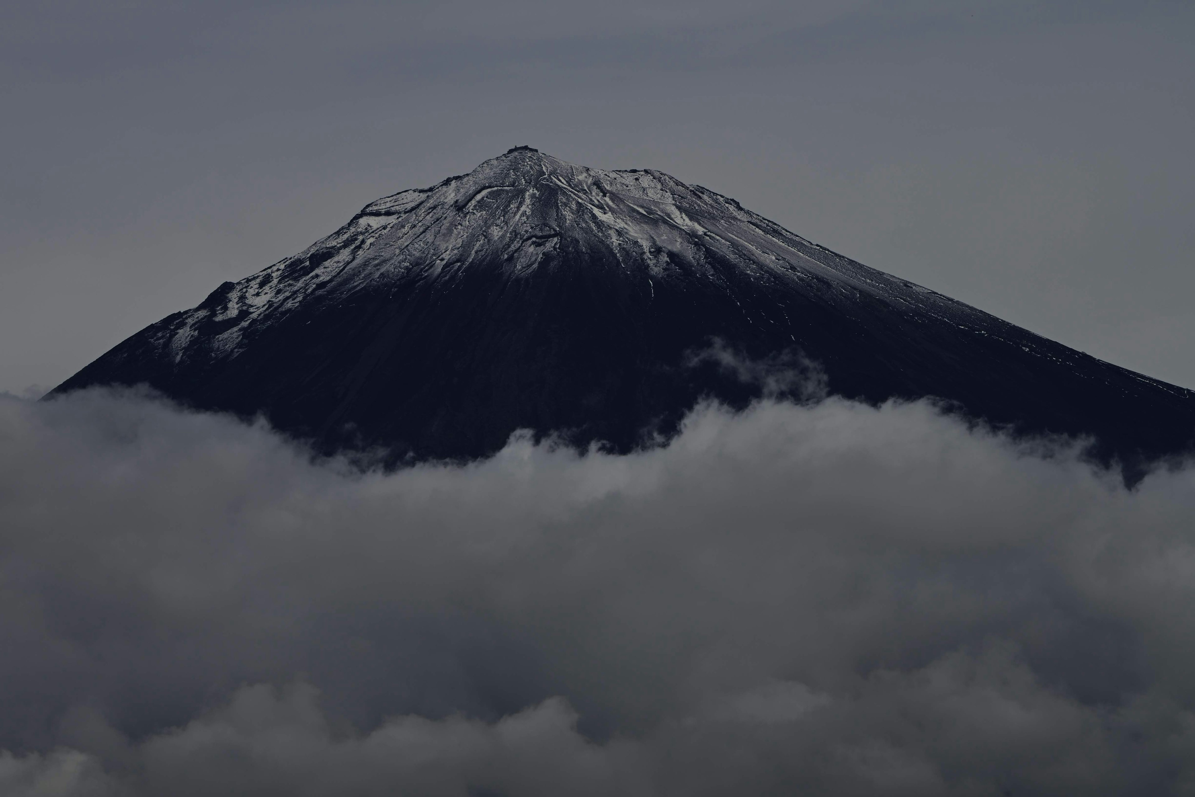 雪をかぶった山が雲の上にそびえる風景