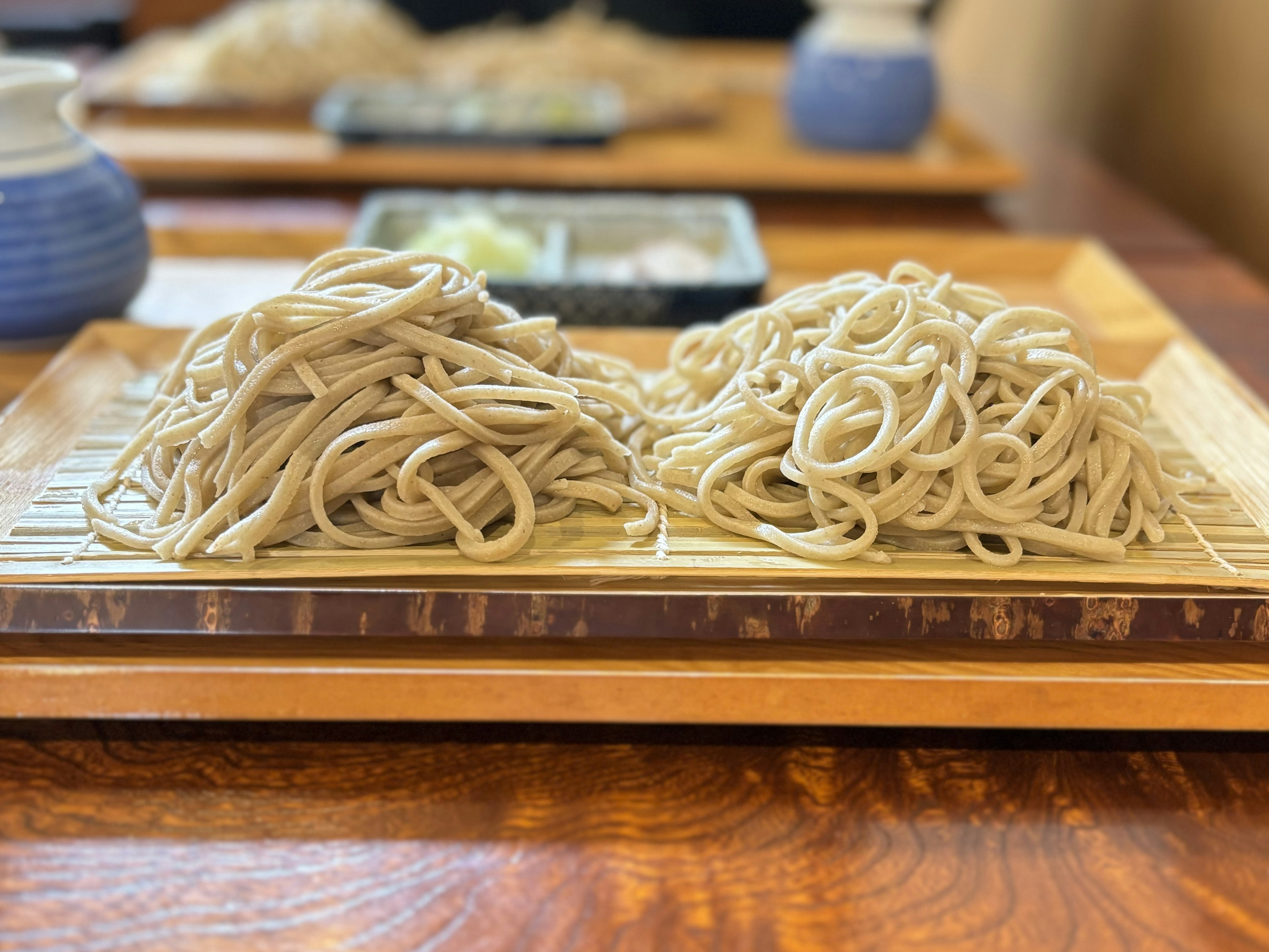 二つの盛り付けられた蕎麦が木の板の上に置かれている