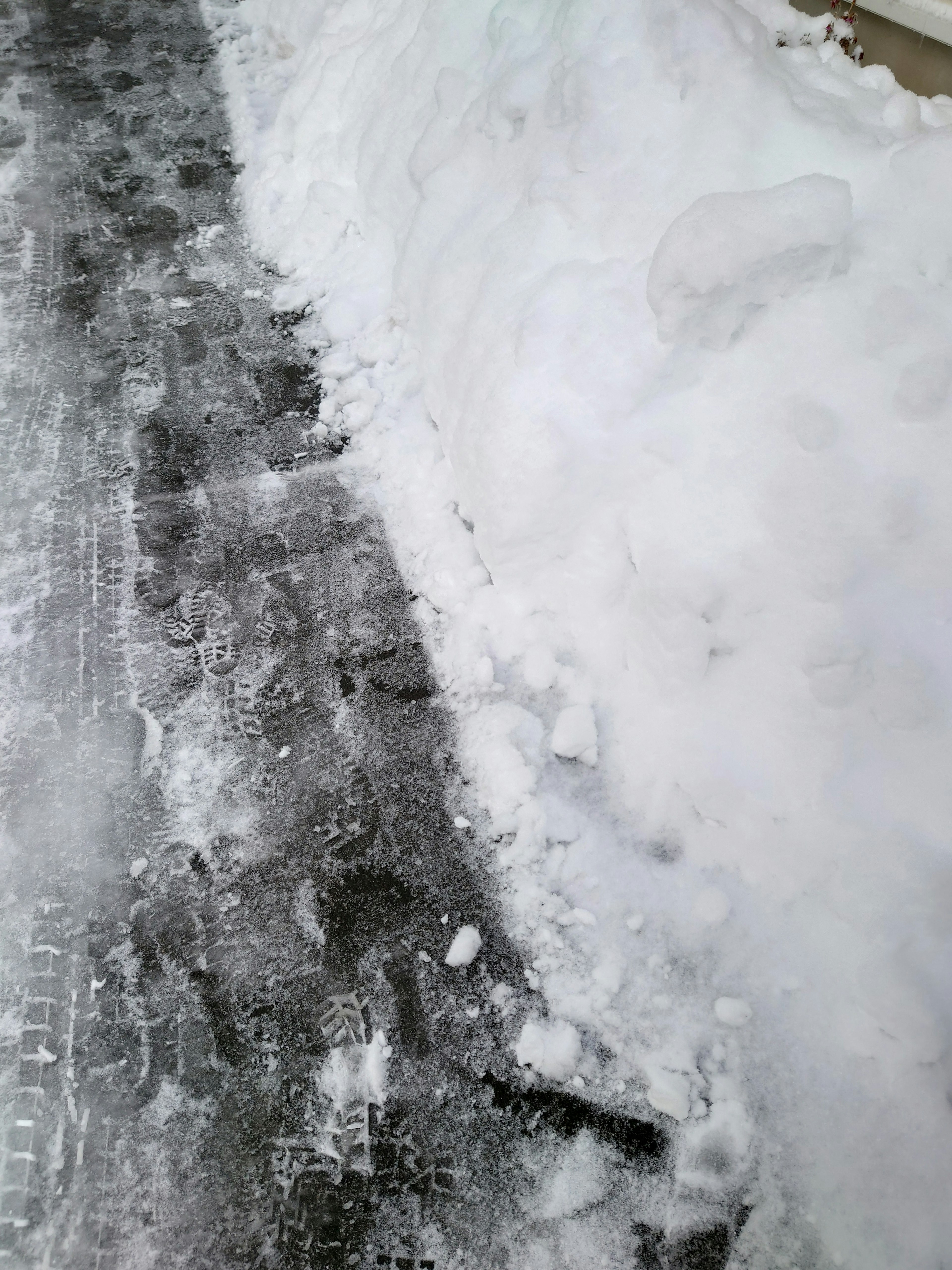 Schneebedeckter Gehweg mit einem Schneehaufen