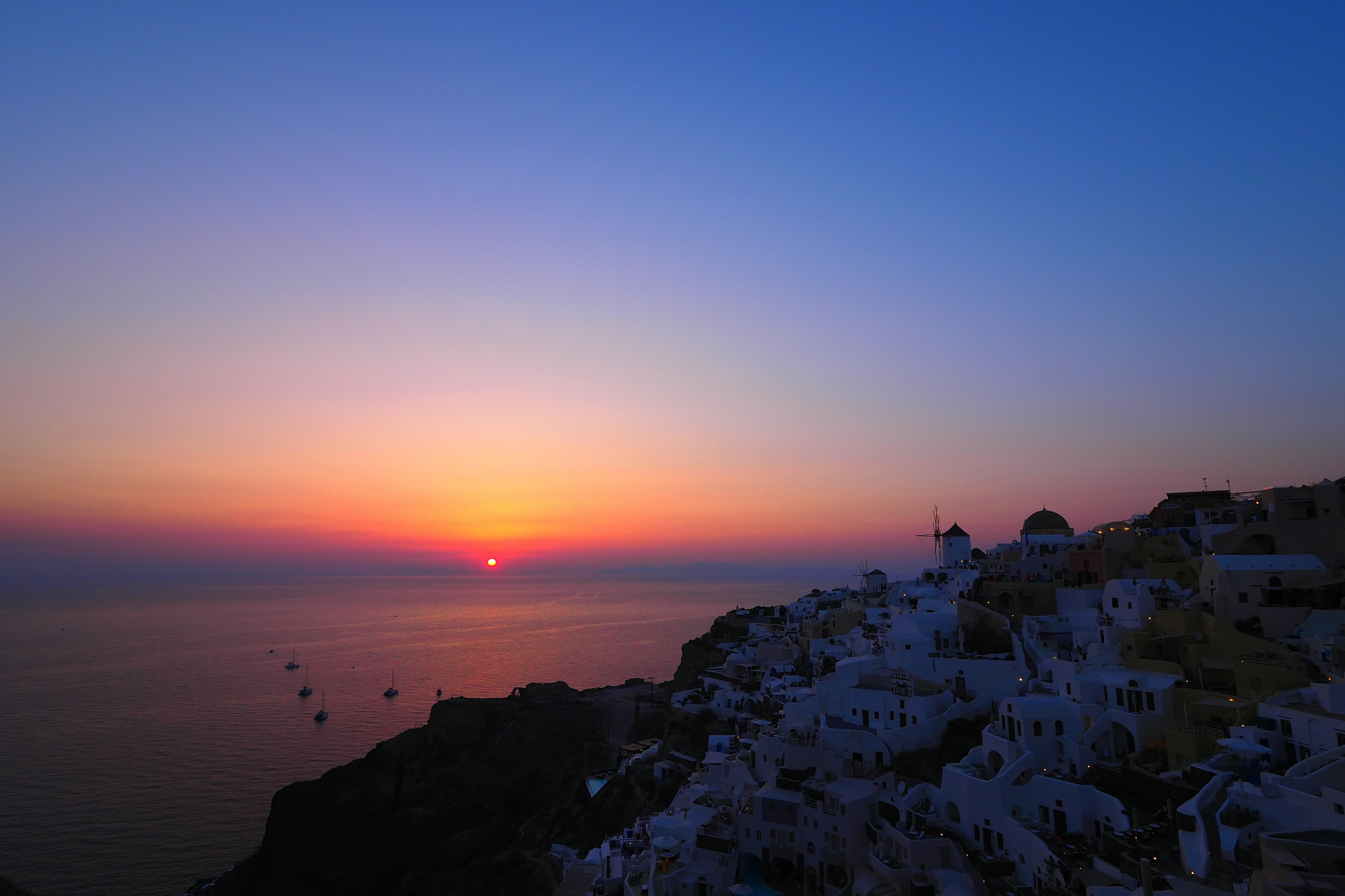 サントリーニ島の美しい夕日と青い空の風景 住宅が崖に沿って並ぶ