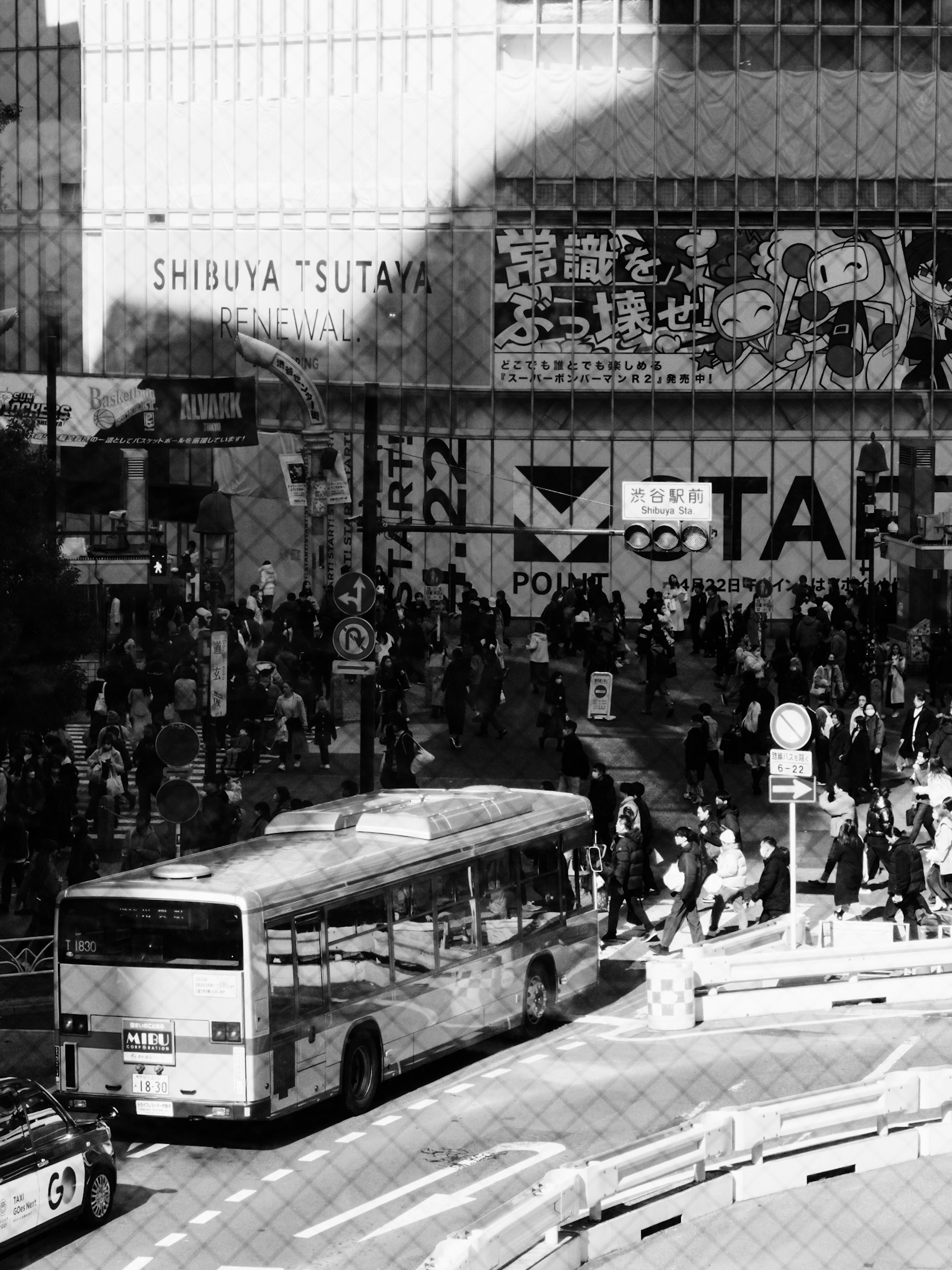 Black and white image of Shibuya with a crowded street and a bus