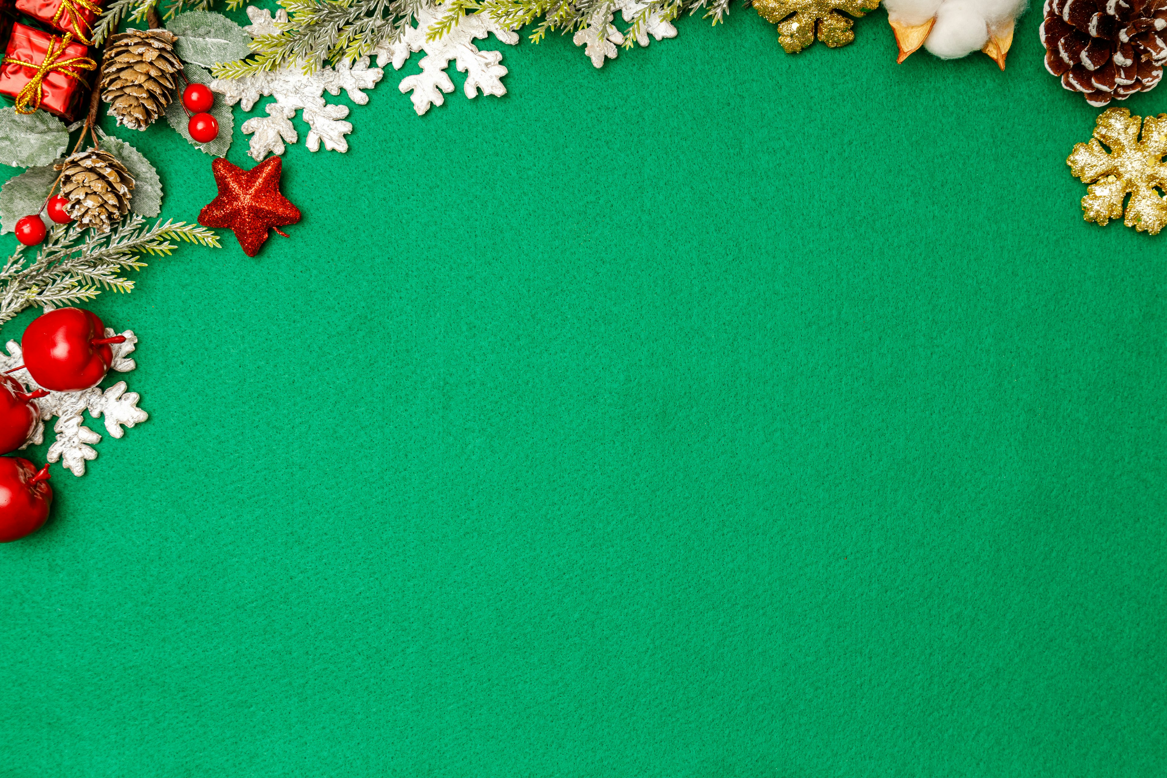 Image with Christmas decorations on a green background including pine cones red balls snowflakes and star ornaments