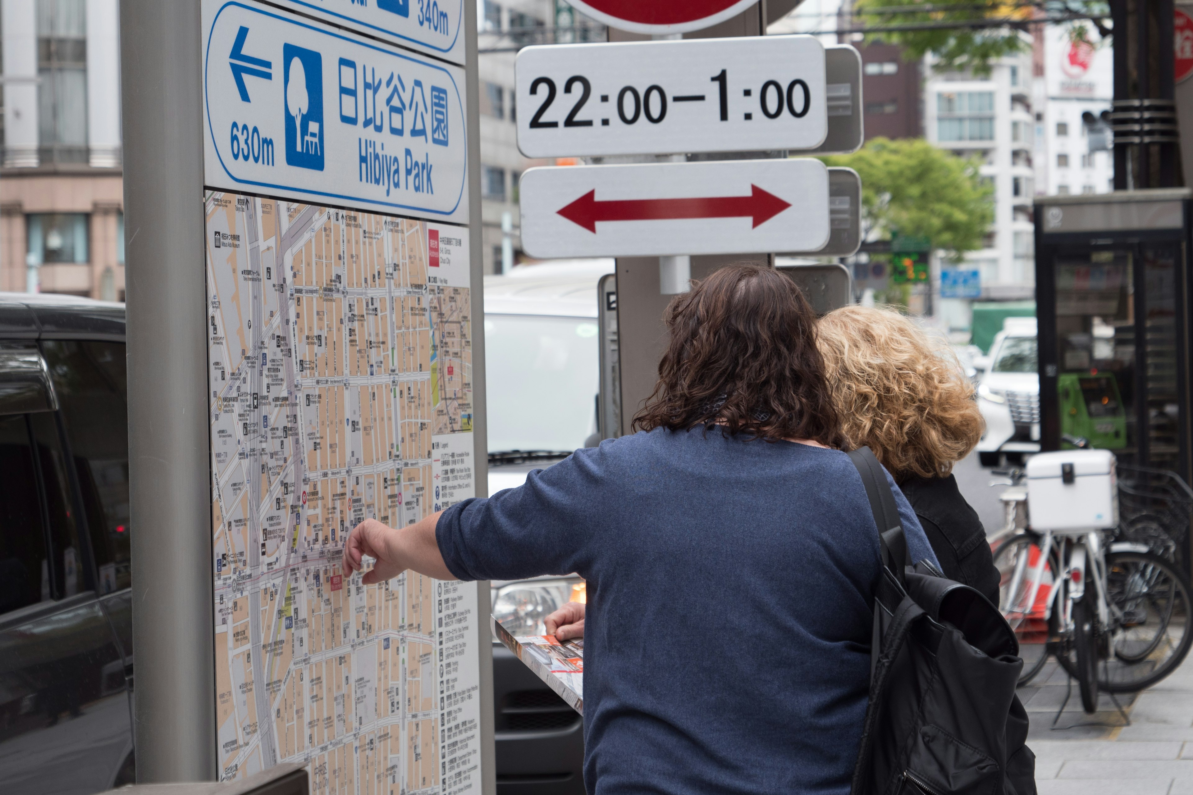 Pareja señalando un mapa con un letrero de horario arriba