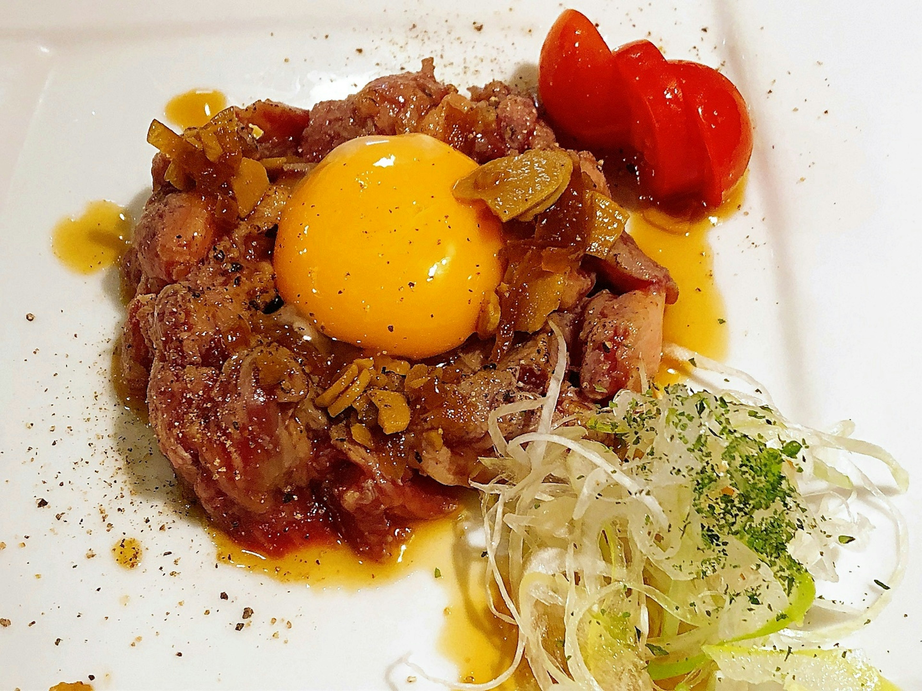 Beef tartare with raw egg yolk and garnishes on a plate